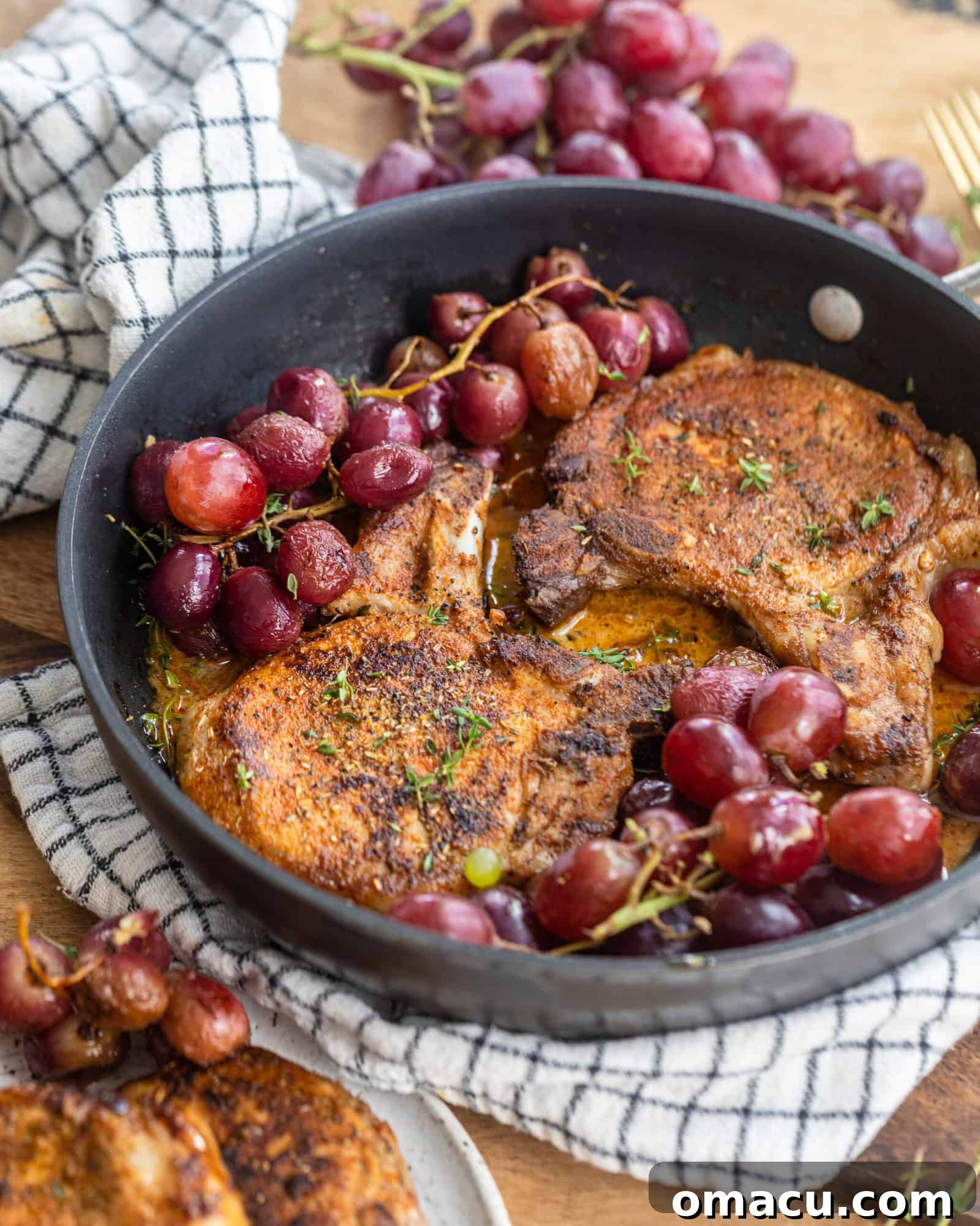 Succulent Garlic Rosemary Pork Chops in a skillet with sweet roasted red grapes, ready to serve.