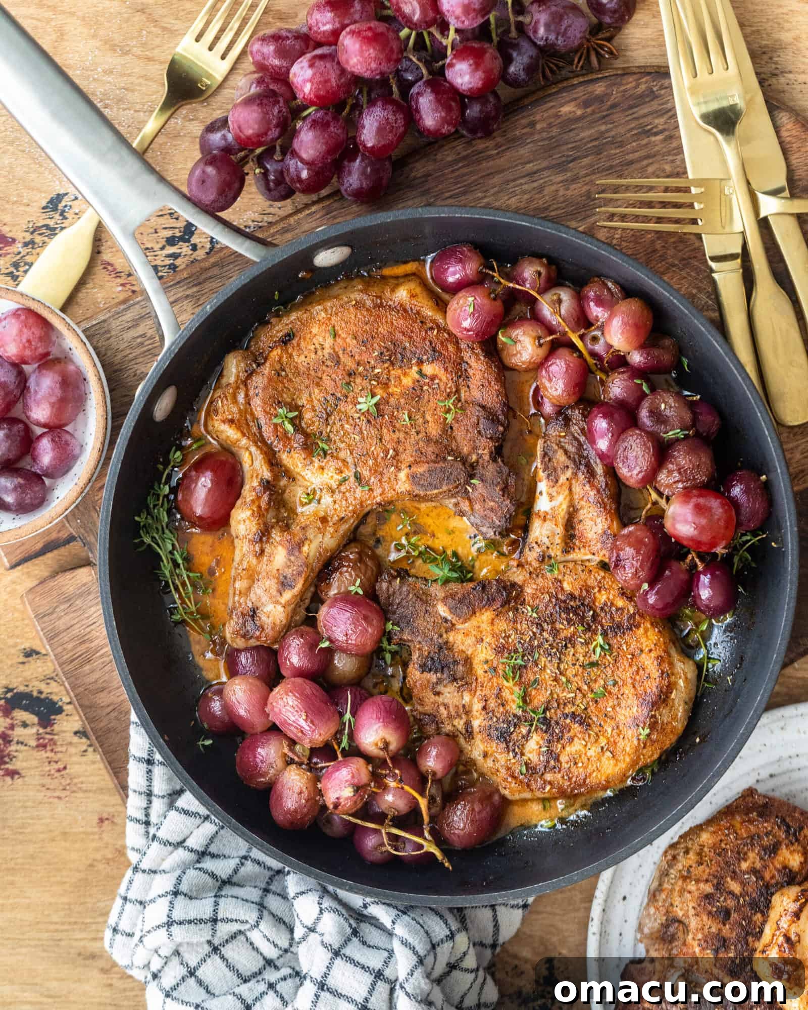 Garlic Rosemary Pork Chops and roasted grapes presented beautifully in a cooking pan.