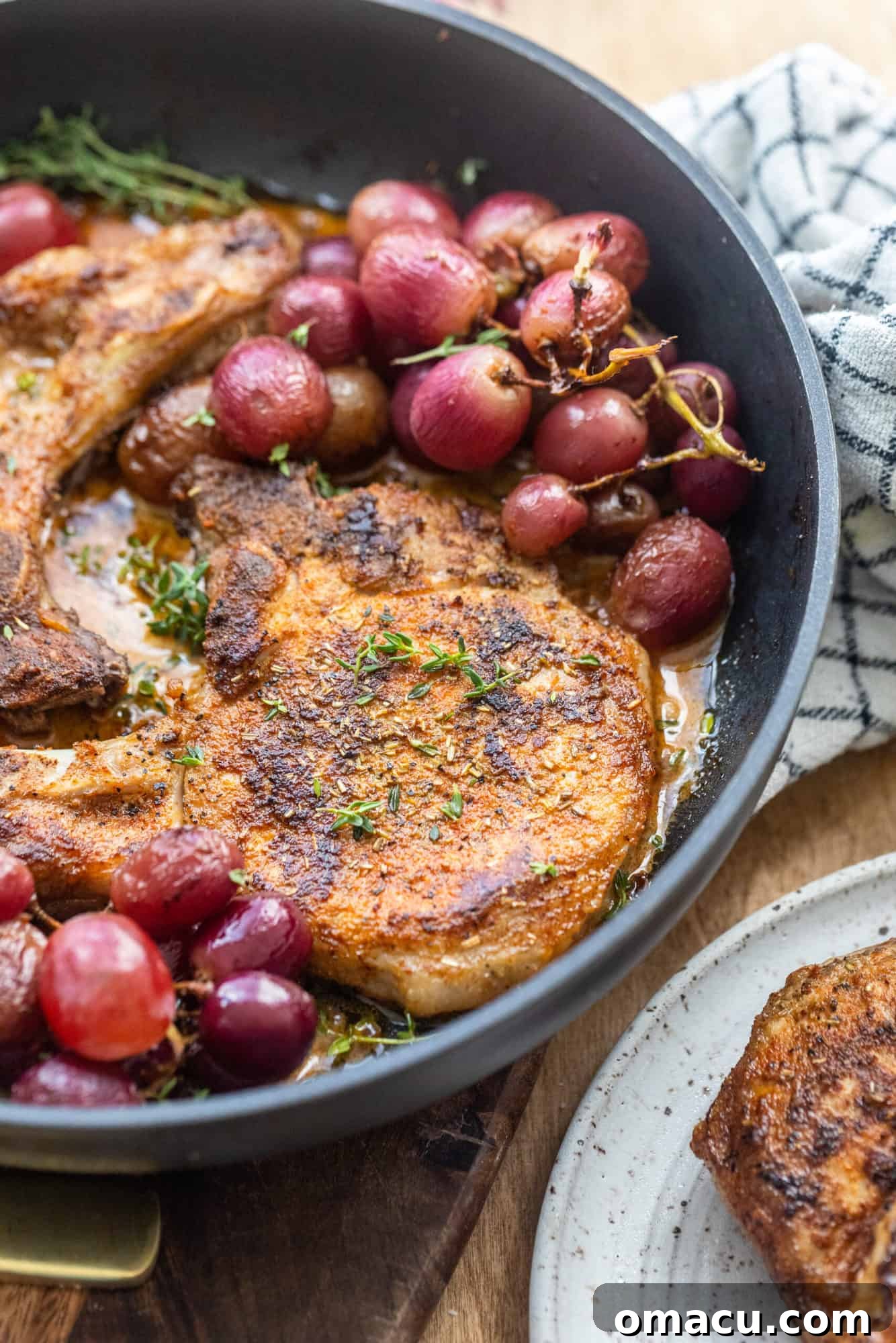Perfectly seared pork chops with glistening roasted grapes, still in the oven-safe pan.
