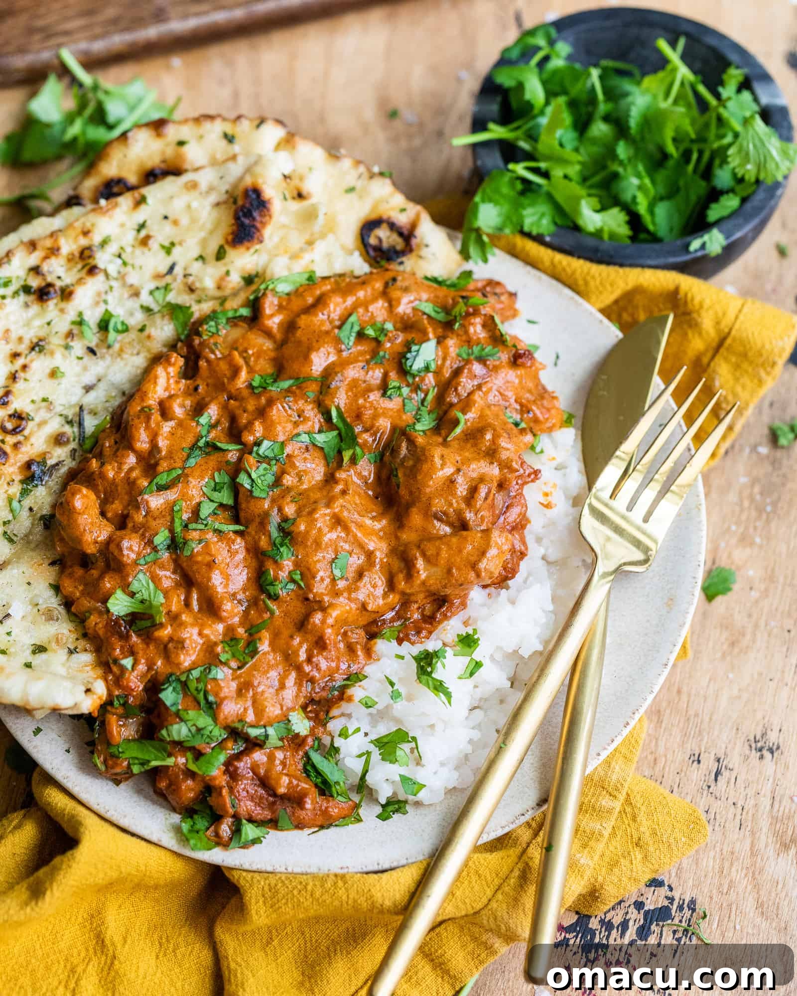 Better than takeout butter chicken served on a plate with fluffy naan and a side of basmati rice