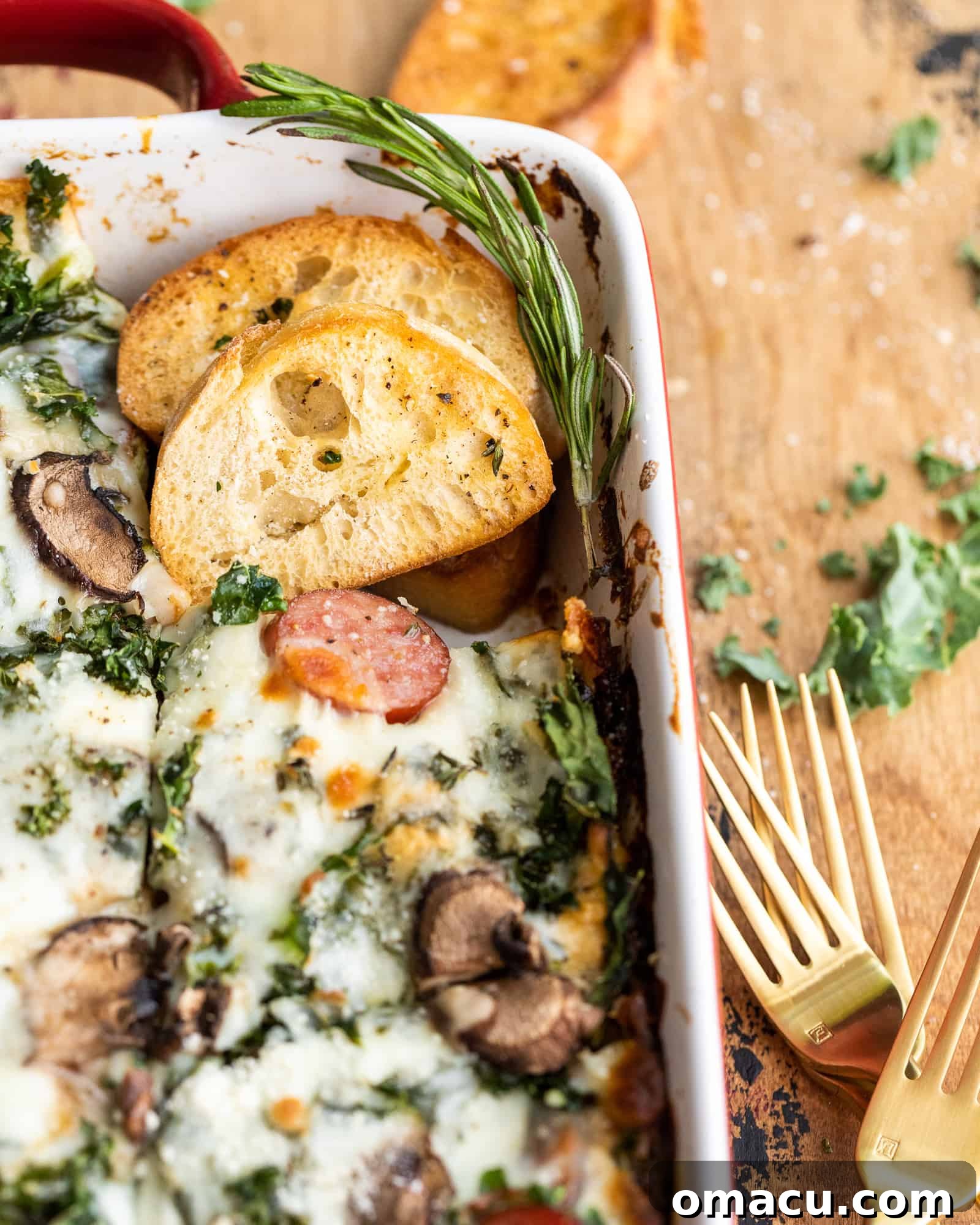 A delectable shot of Roasted Garlic Sausage Kale and Mushroom Lasagna in a baking dish, served with a slice of crusty bread.