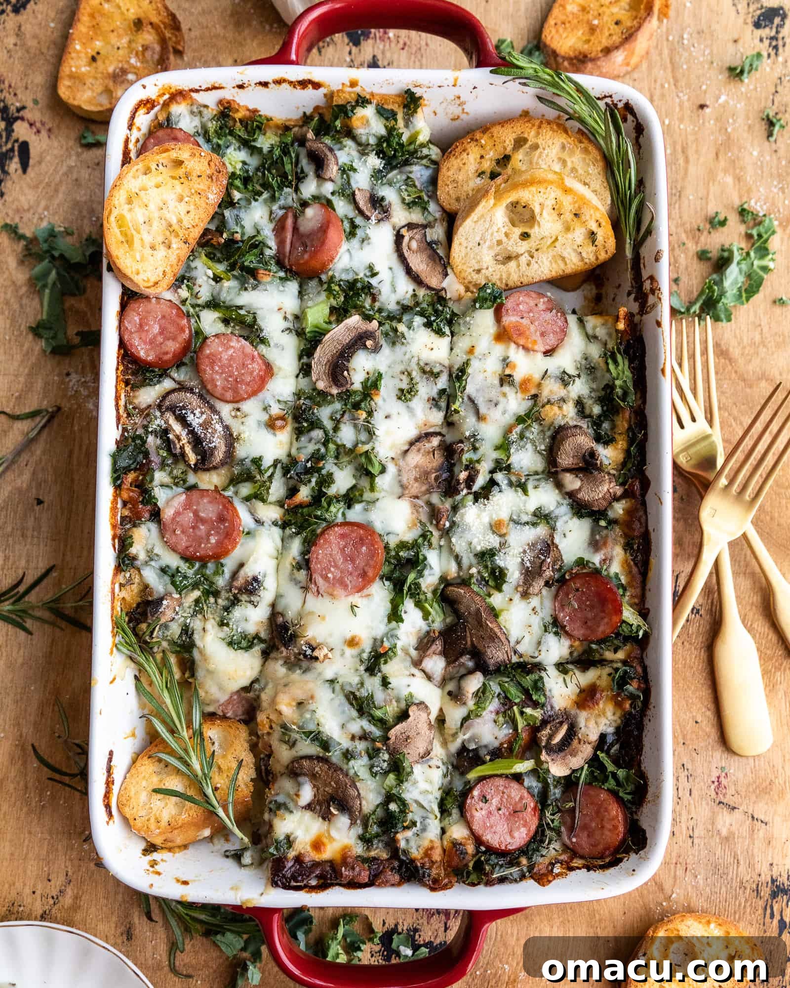 A close-up view of Roasted Garlic Sausage Kale and Mushroom Lasagna in a baking dish with several pieces already cut and removed, revealing the rich layers.