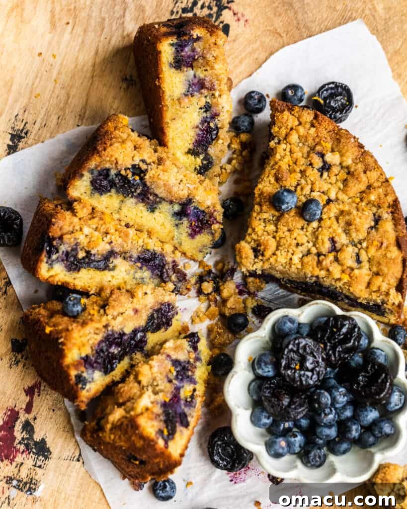 sliced buckle on a serving tray with a bowl of blueberries and prunes on the side