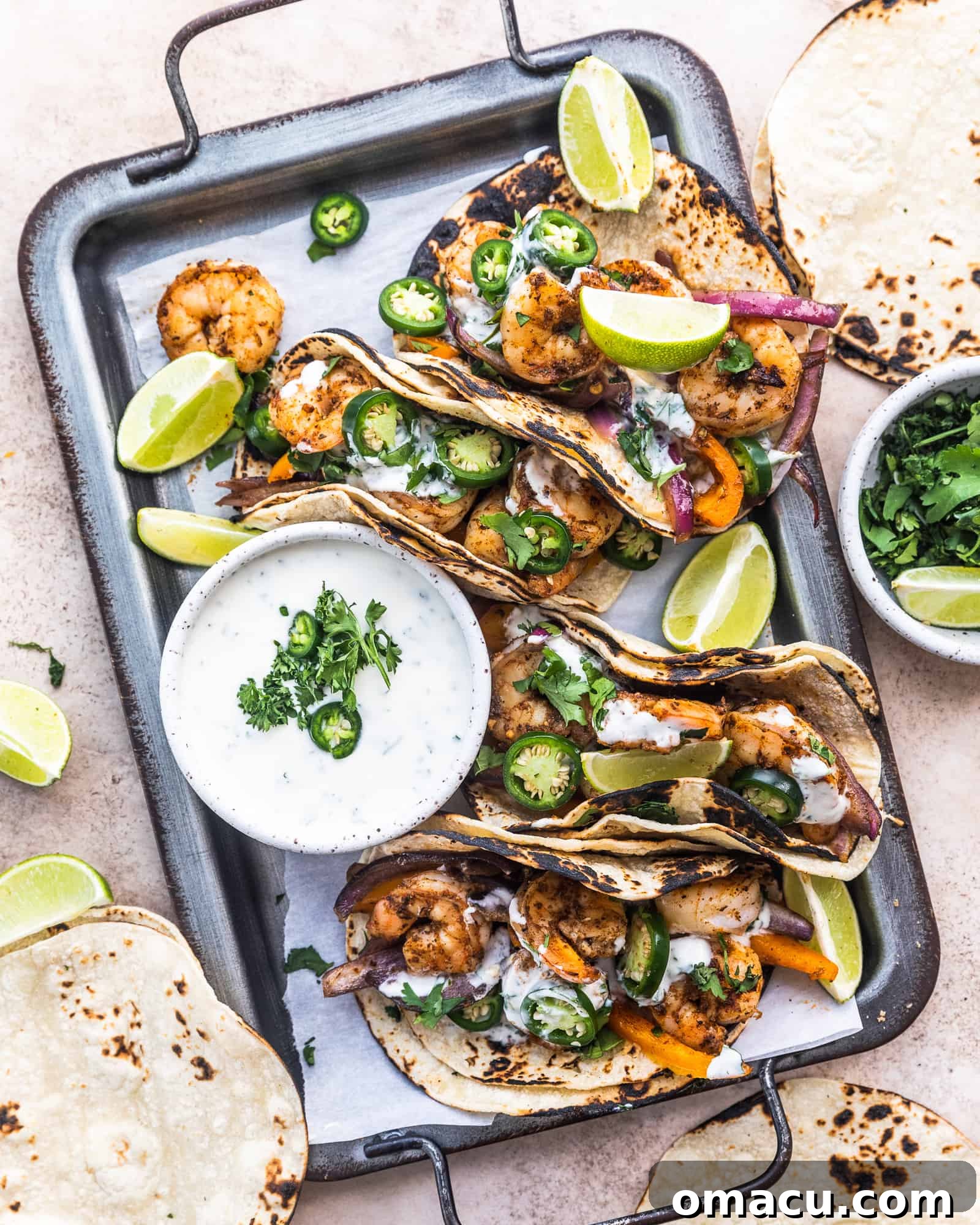four cajun shrimp tacos on a serving tray with ranch dipping sauce and limes