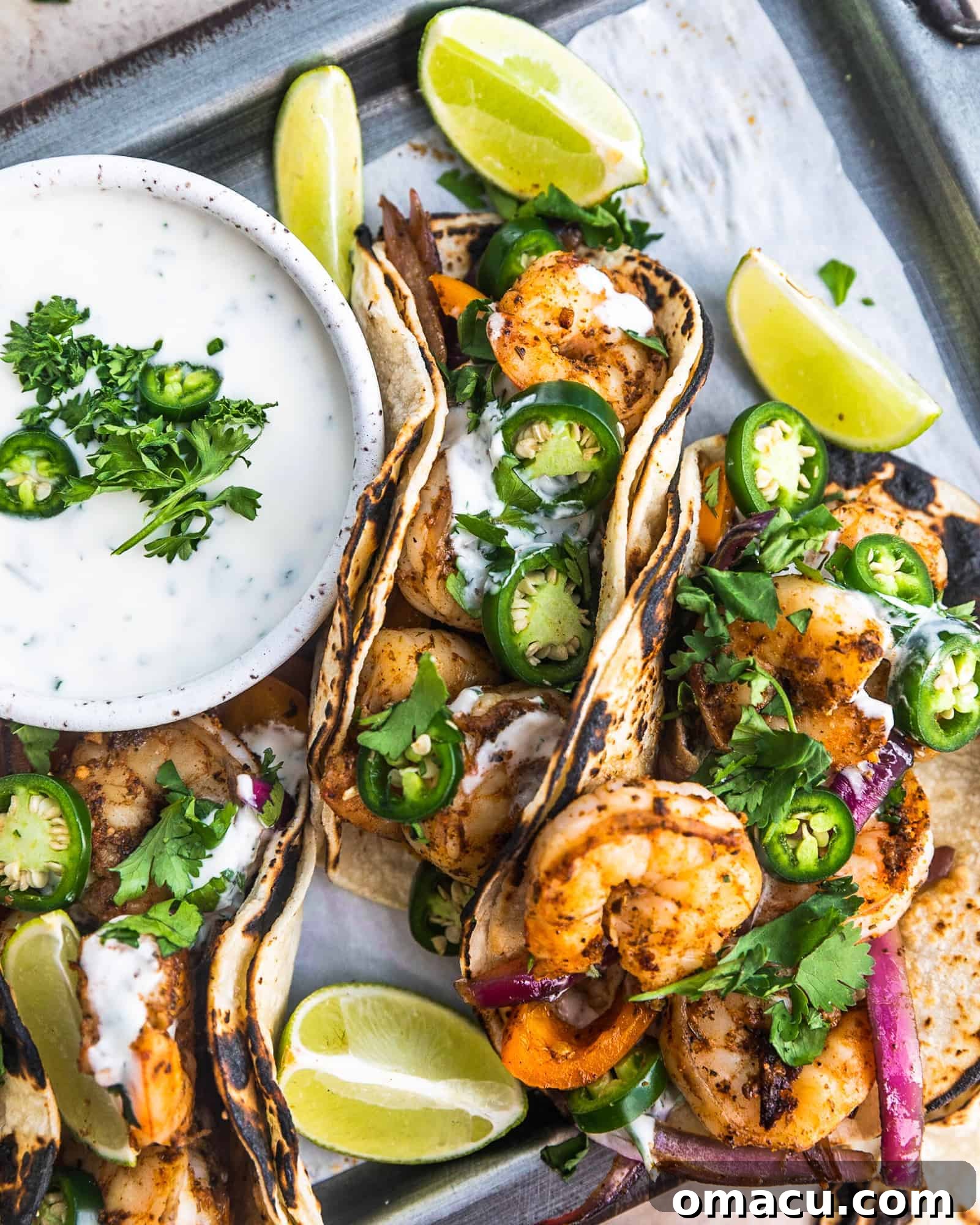 cajun shrimp tacos on a serving tray with limes and ranch sauce close-up