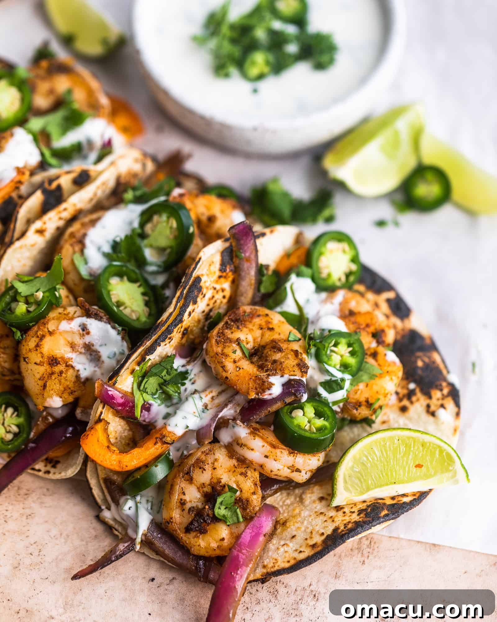 cajun shrimp tacos on parchment paper with limes and garlic lime ranch sauce close-up