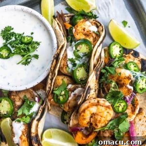cajun shrimp tacos on a serving tray with limes and ranch sauce