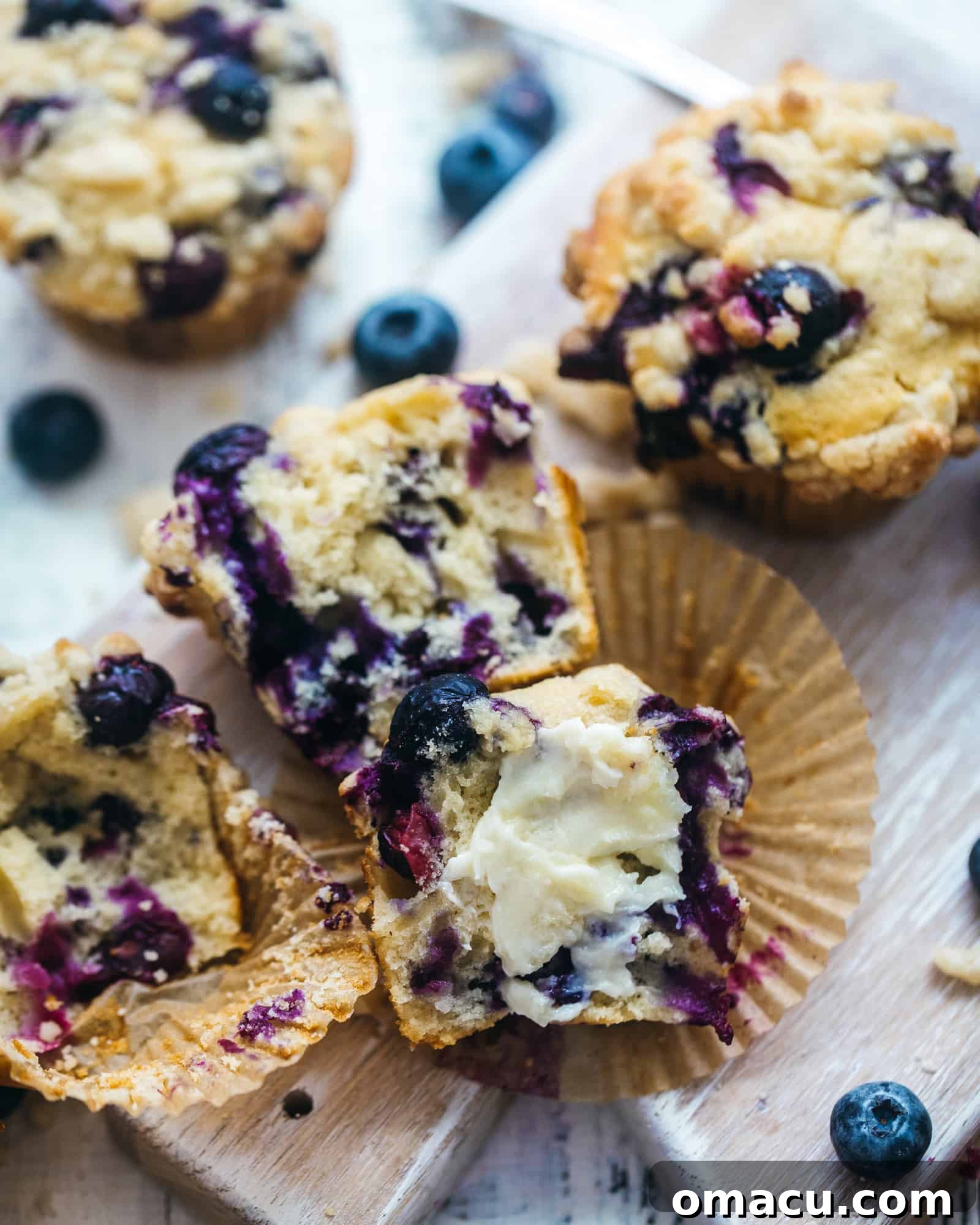 A blueberry muffin expertly cut in half, revealing its moist interior and ready for a pat of butter