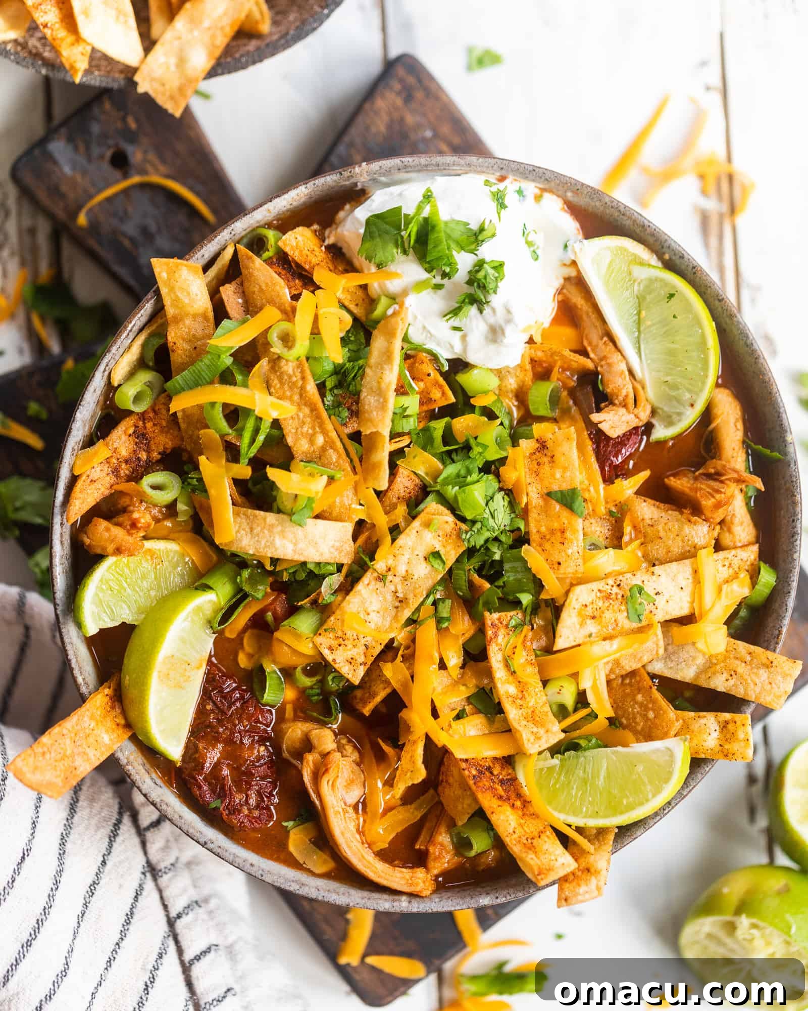 spicy chicken tortilla soup with lime on a cutting board