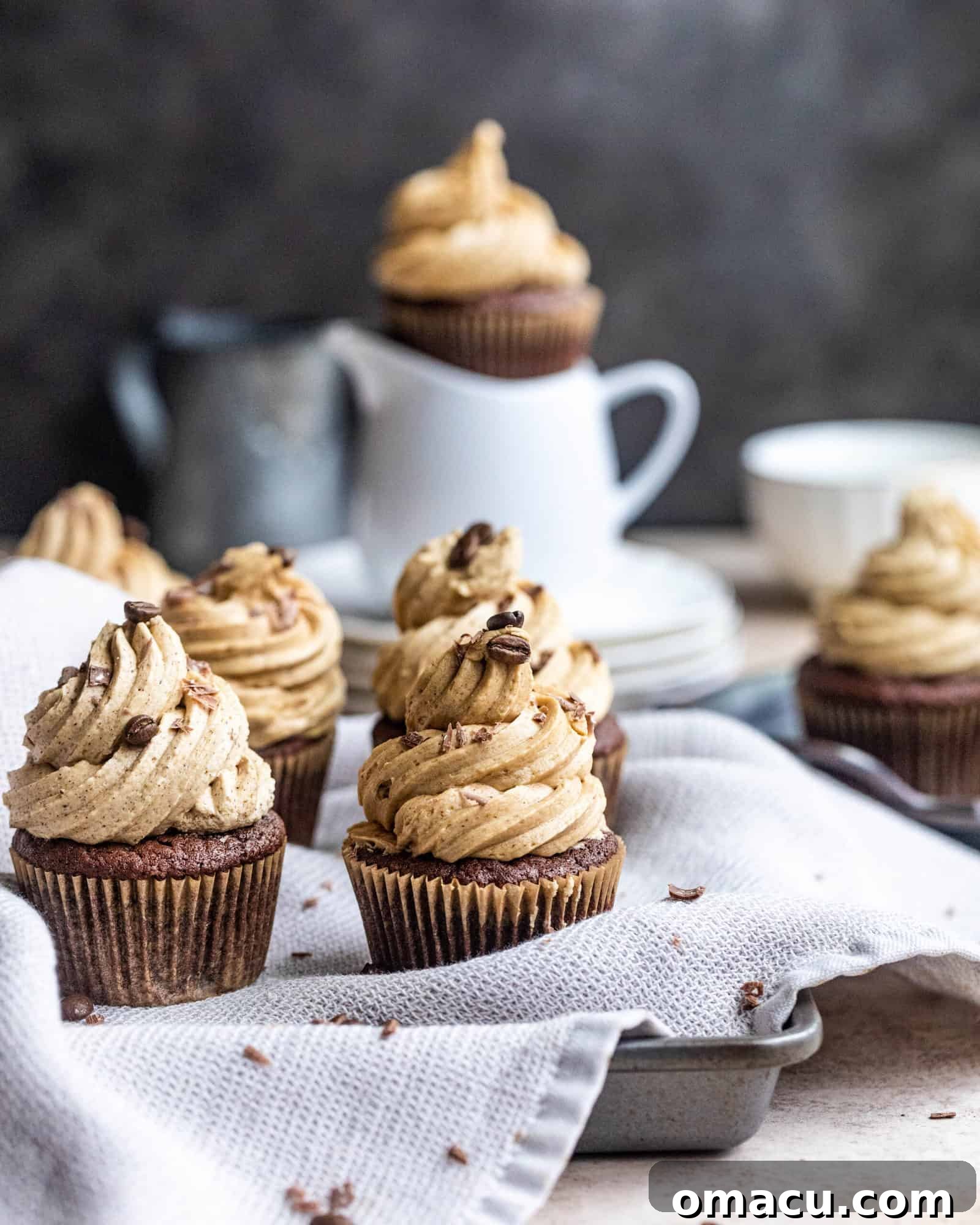 chocolate cupcakes with espresso buttercream cooling in a baking sheet with a dish cloth