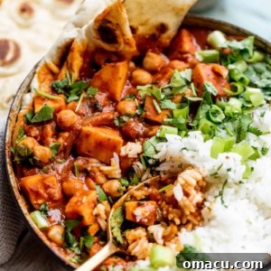 A top-down view of a bowl of Sweet Potato Chickpea Curry, garnished with fresh cilantro and a swirl of coconut cream, ready to eat.