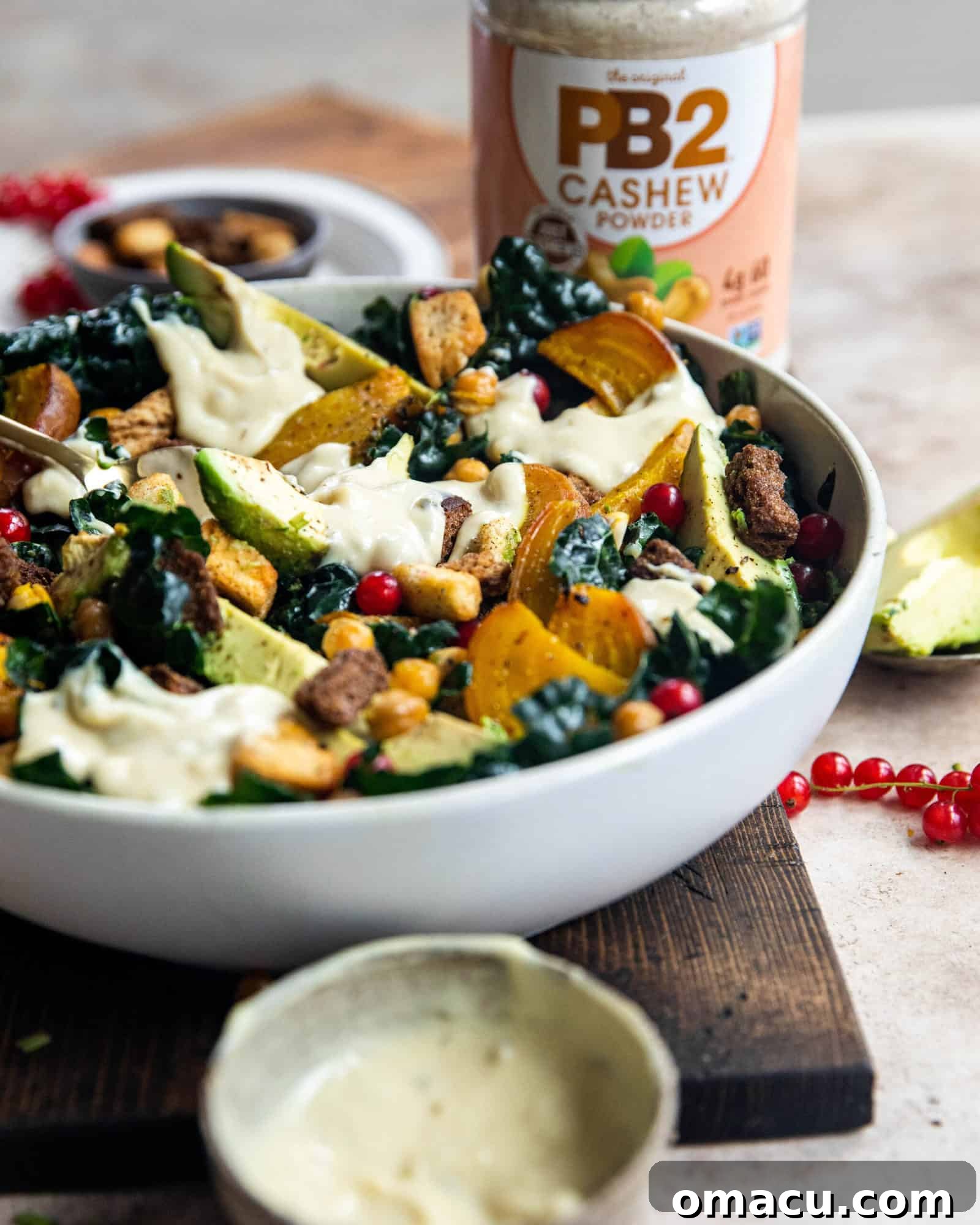 Close-up of vegan kale caesar salad dressing being drizzled over the salad, emphasizing the creamy texture and inviting appearance.