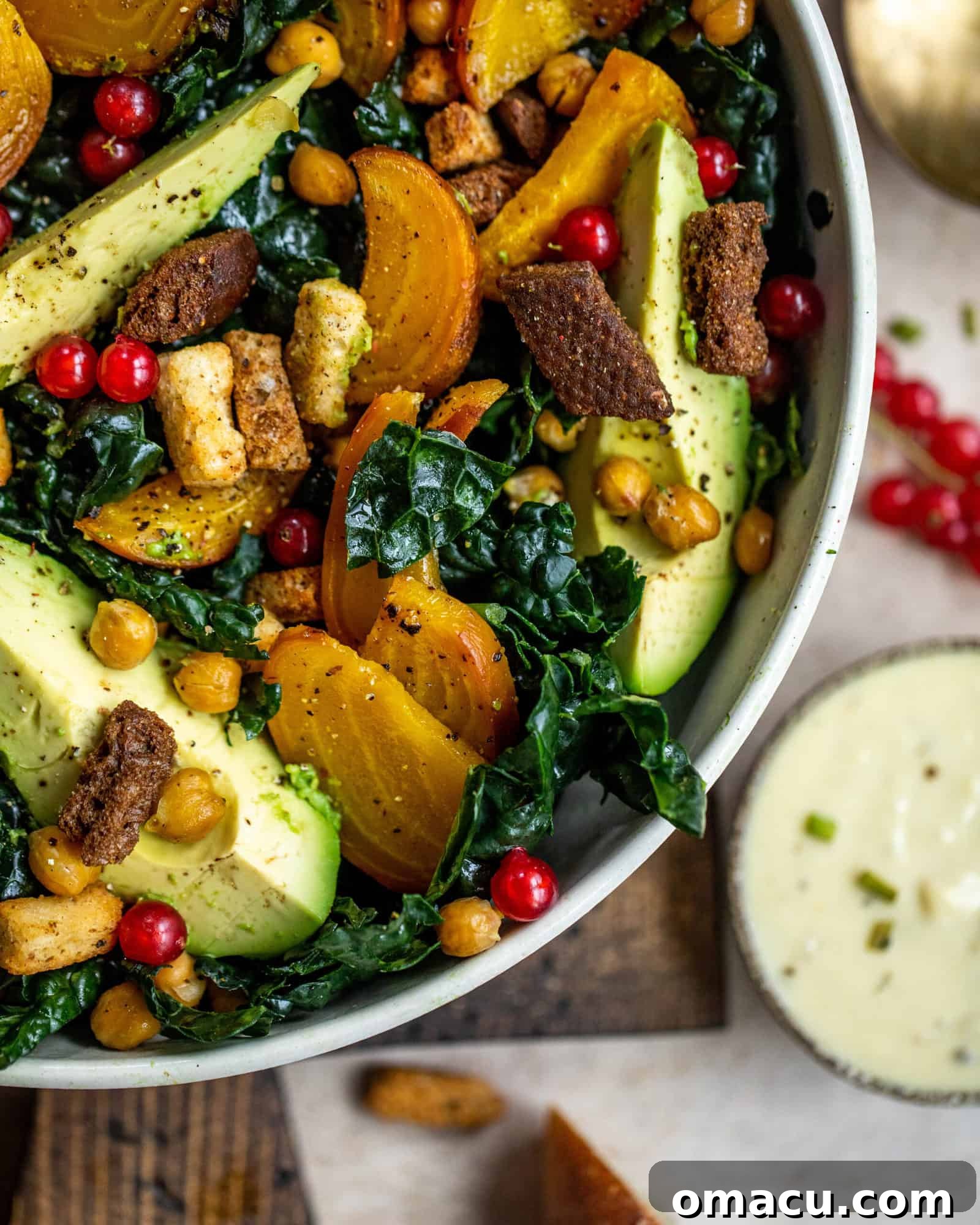 A large bowl of vegan kale caesar salad with a separate small bowl of the homemade caesar dressing on the side, ready to be mixed.