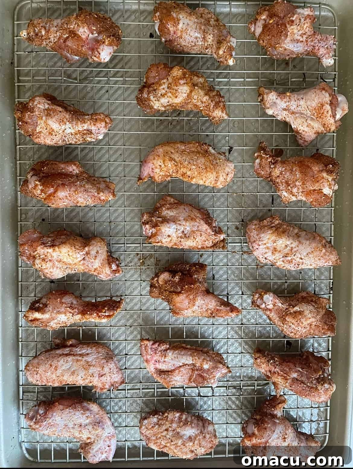 Crispy chicken wings resting on a cooling rack after baking, ready for saucing.
