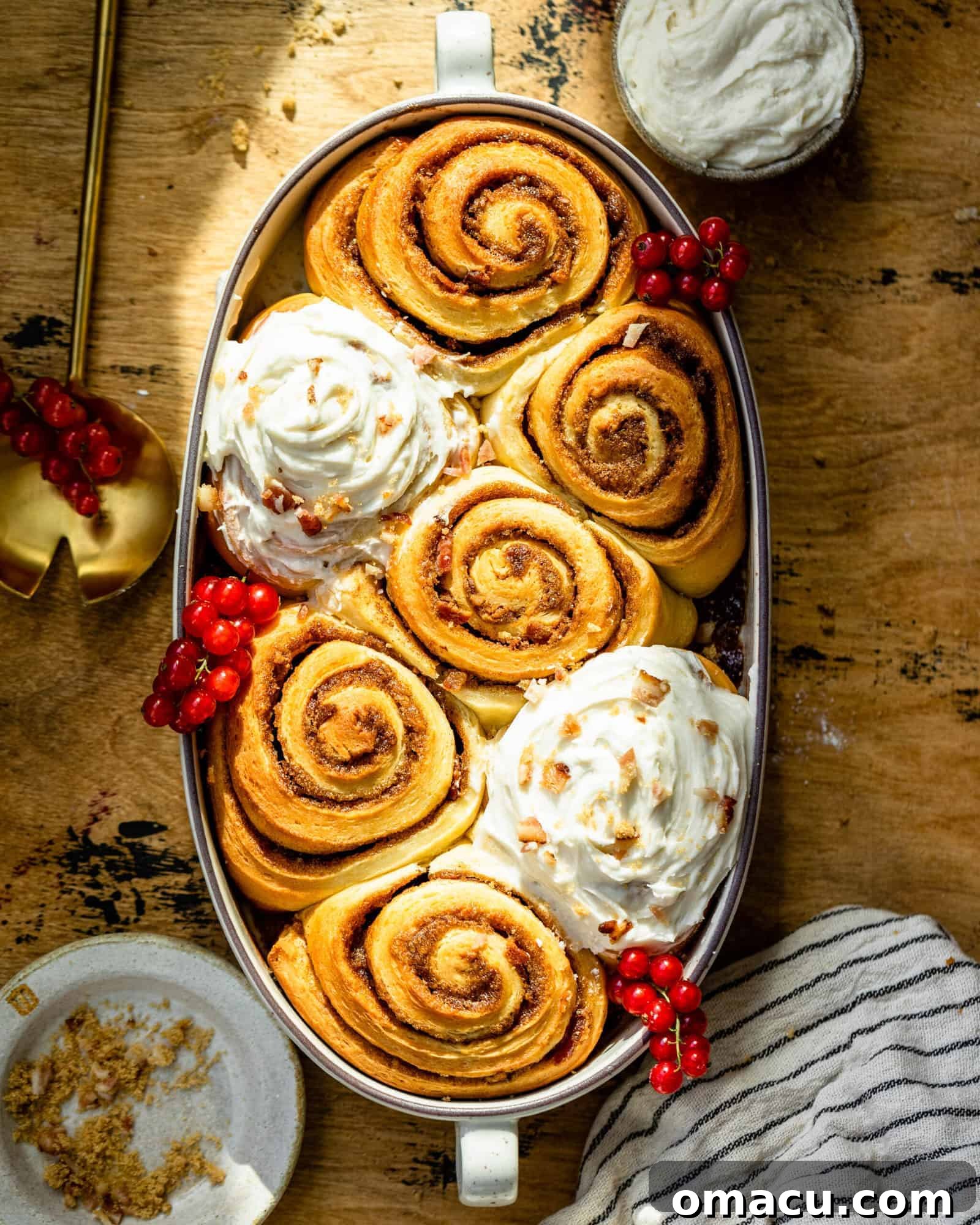 A warm baking dish filled with freshly baked Maple Bacon Cinnamon Rolls, glistening with maple icing and sprinkled with bacon bits.