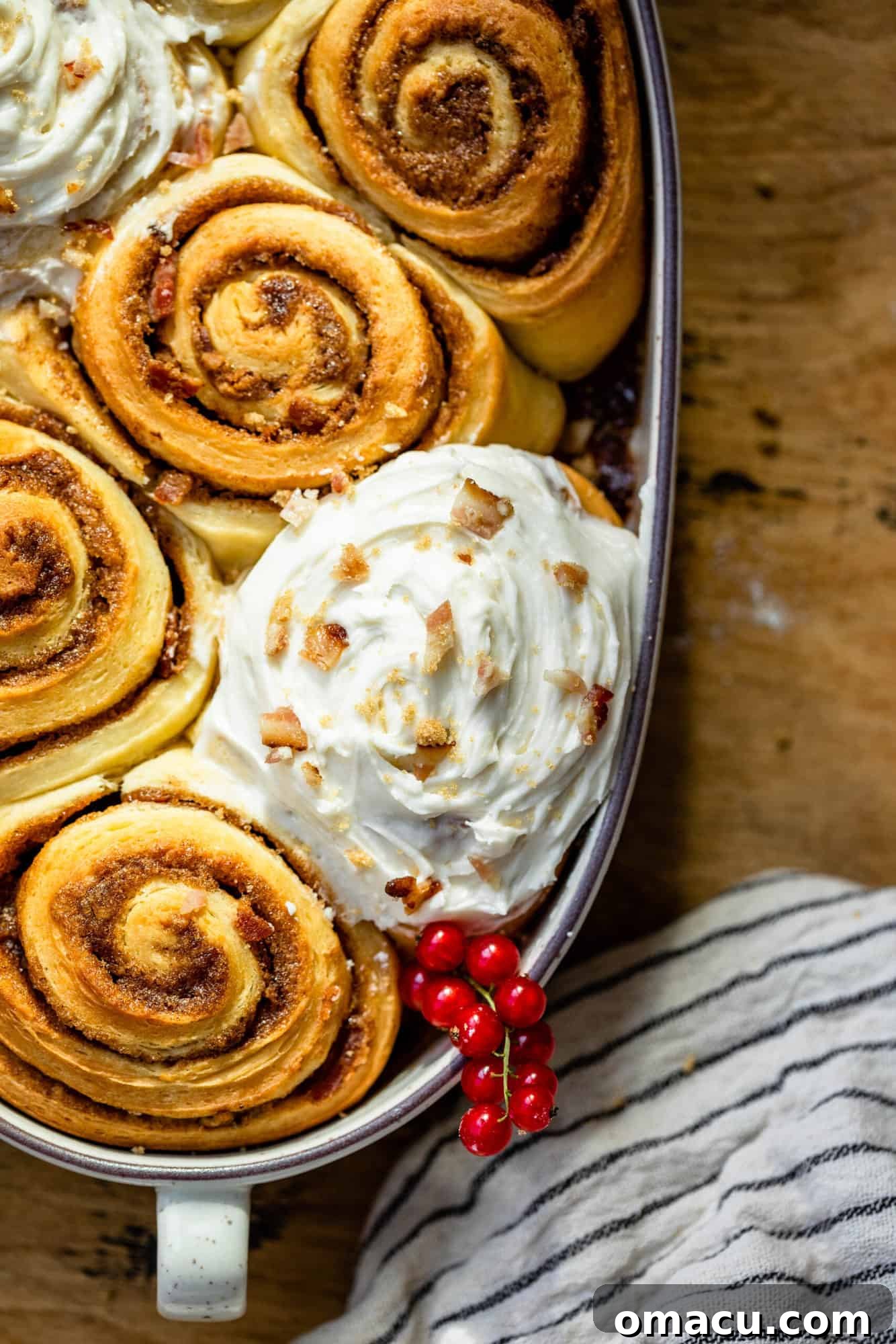 Close-up of baked cinnamon rolls with a generous layer of white icing on top, ready to be served.