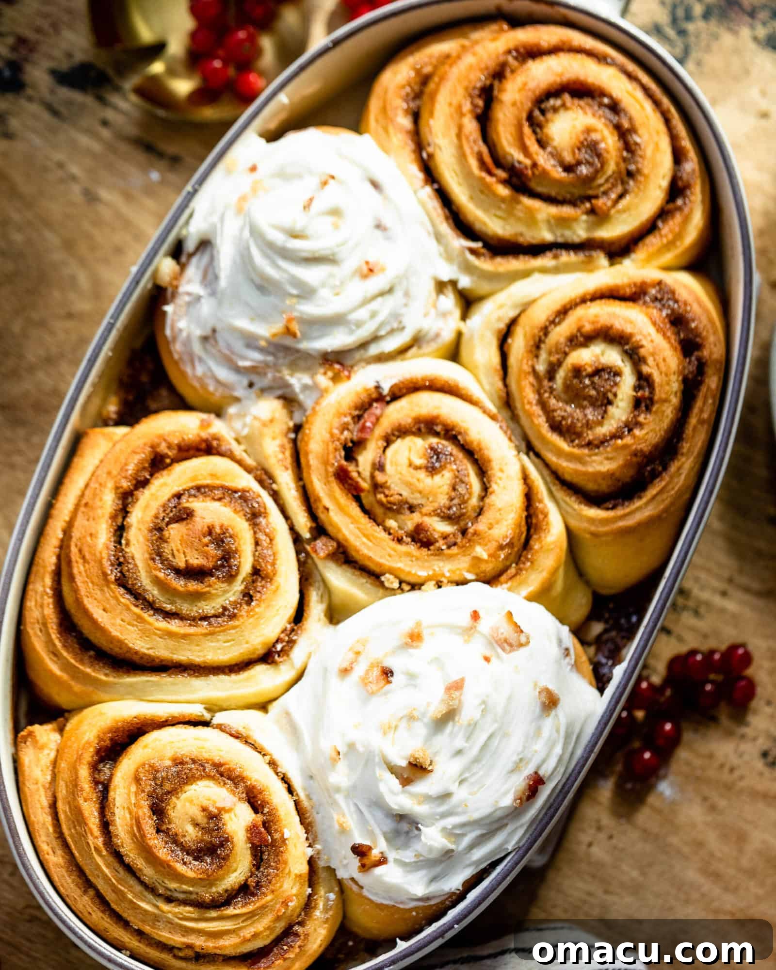 Multiple freshly baked Maple Bacon Cinnamon Rolls in a rectangular baking dish, topped with icing.