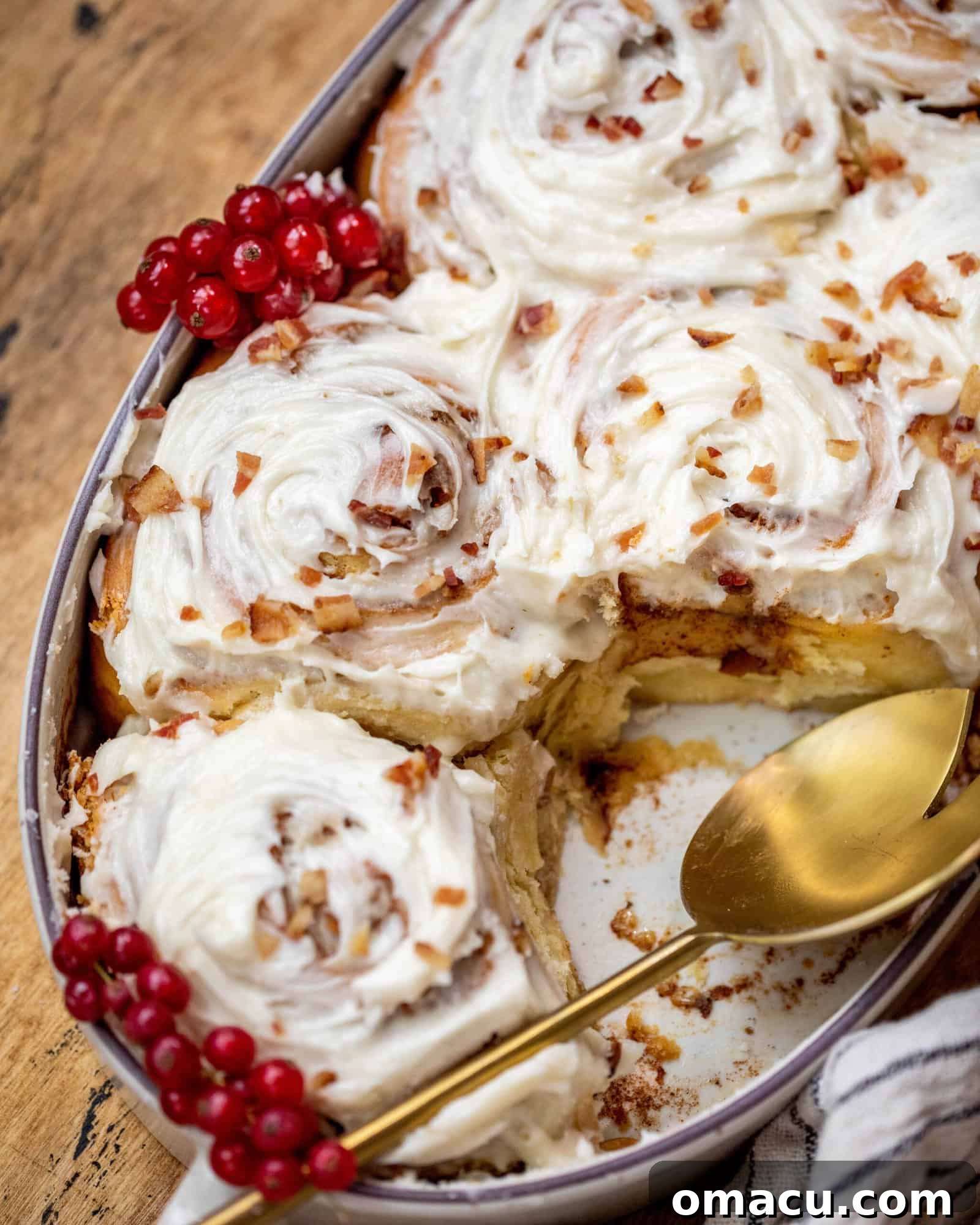 A close-up shot of Maple Bacon Cinnamon Rolls, with the gooey filling visible in the swirls and a rich maple icing on top.