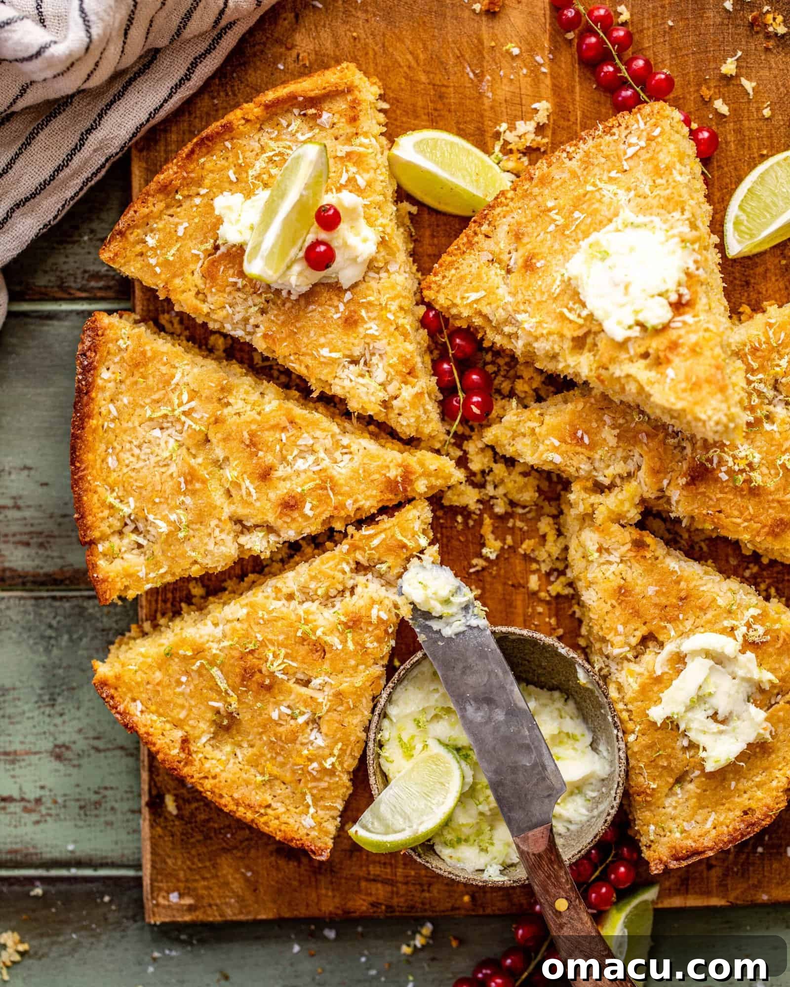 A beautifully textured coconut cornbread loaf, adorned with a dollop of sweet lime butter, resting on a rustic wooden surface, ready to be served.