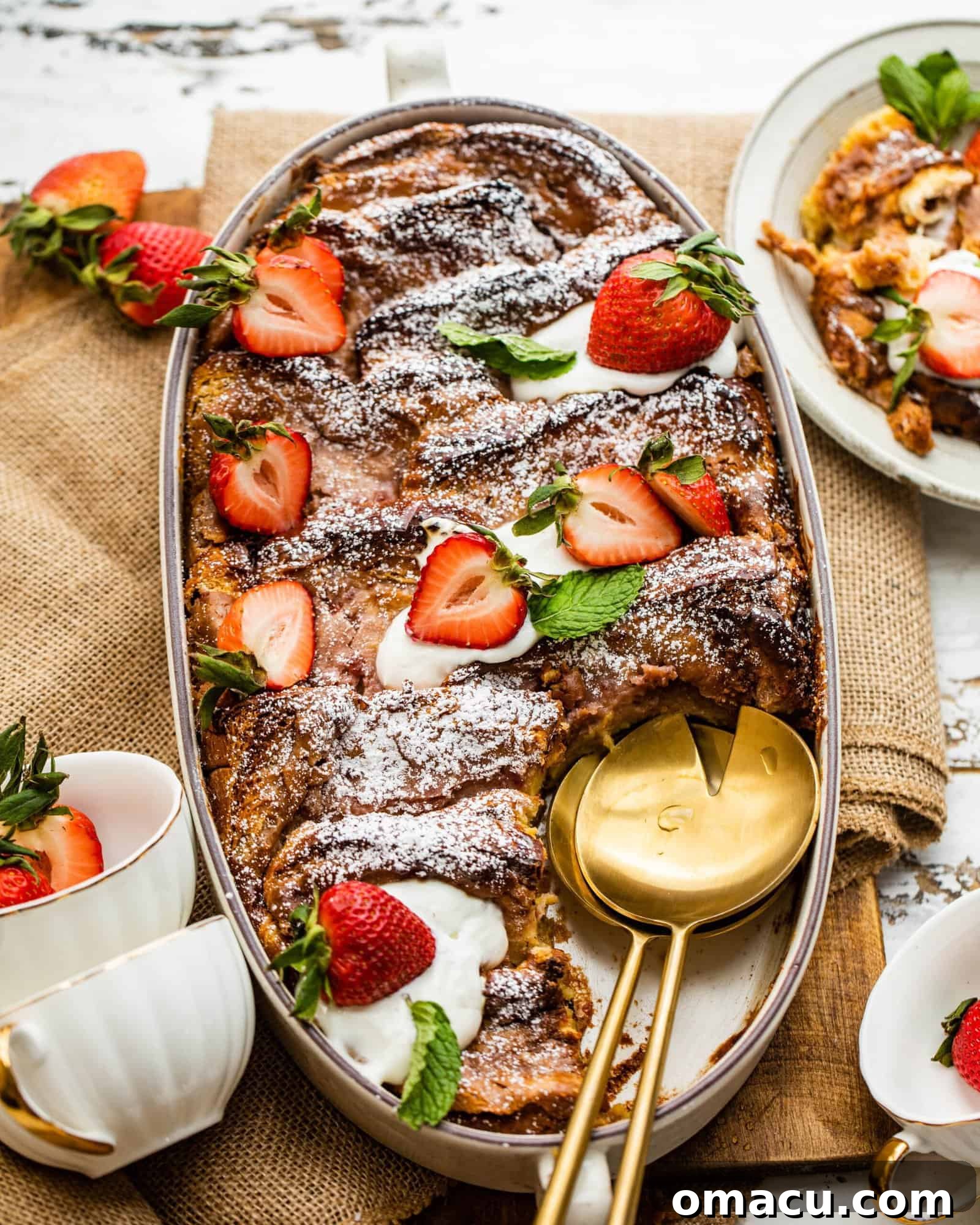 Strawberry French Toast Casserole in a baking dish, garnished with fresh strawberries and a dollop of mascarpone or cream cheese