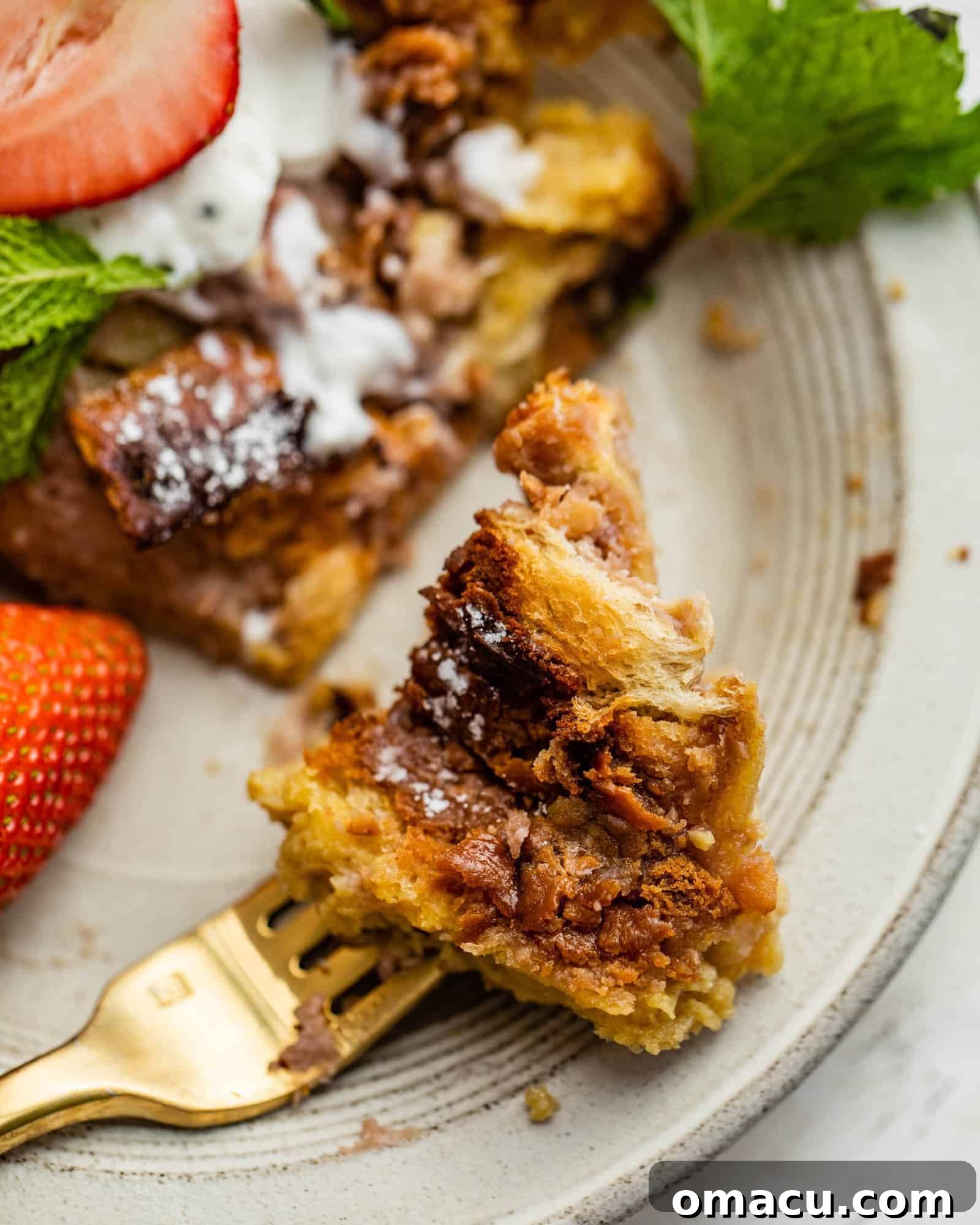 A close-up of a piece of French toast on a fork, showing the fluffy interior and golden crust.