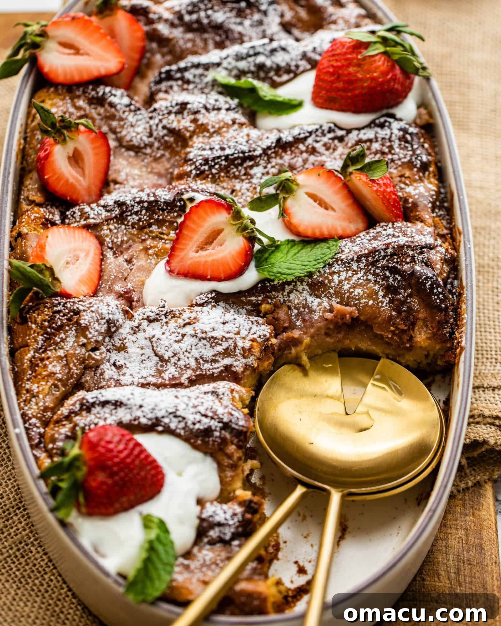 Baked Strawberry French Toast Casserole in a serving dish with a serving spoon, ready to be enjoyed.