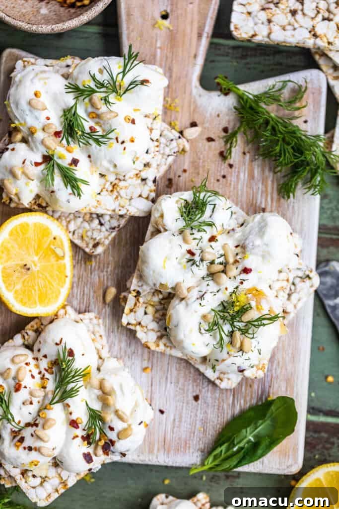 Roasted Garlic Labneh on a rustic serving board, accompanied by crunchy crackers and fresh herbs, ready to be enjoyed as a savory snack or appetizer.