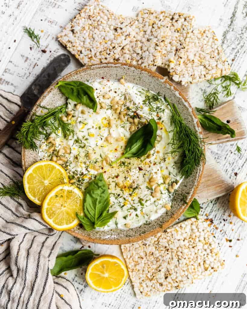 Fresh labneh in a bowl, garnished with vibrant green herbs and a slice of lemon, showcasing its smooth, appealing texture.