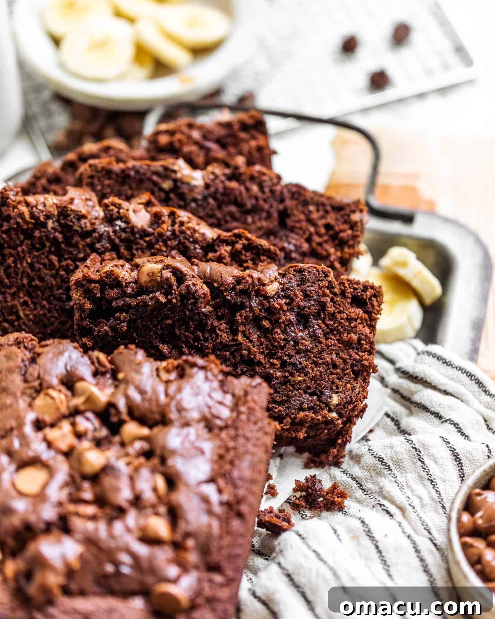 Several slices of rich chocolate banana bread artfully arranged on a white plate, ready to be served.