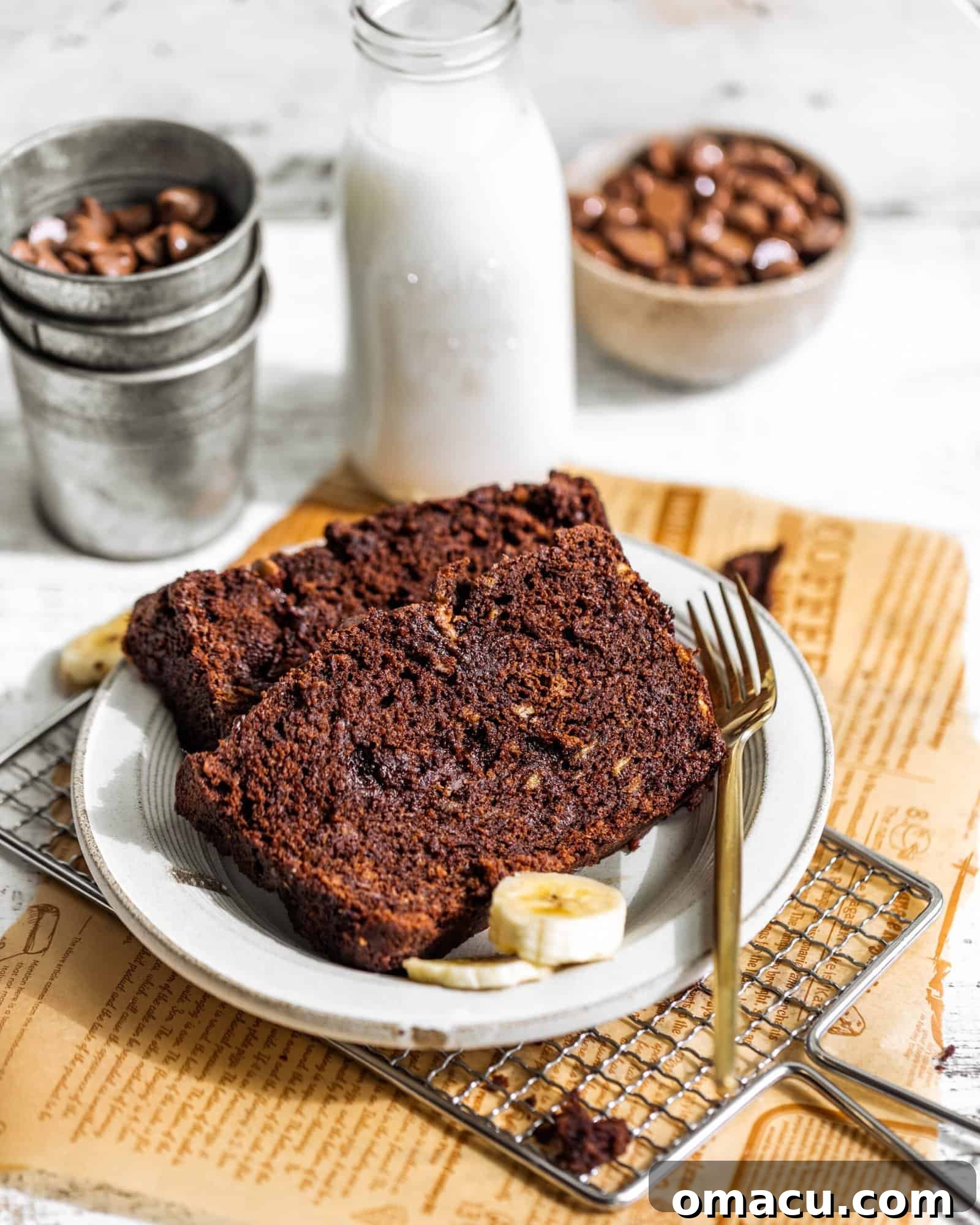 Two generous slices of moist chocolate banana bread presented on a pristine white plate, showcasing their rich color and inviting texture.