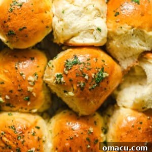 Garlic butter dinner rolls together in a pan, with a warm, inviting glow.