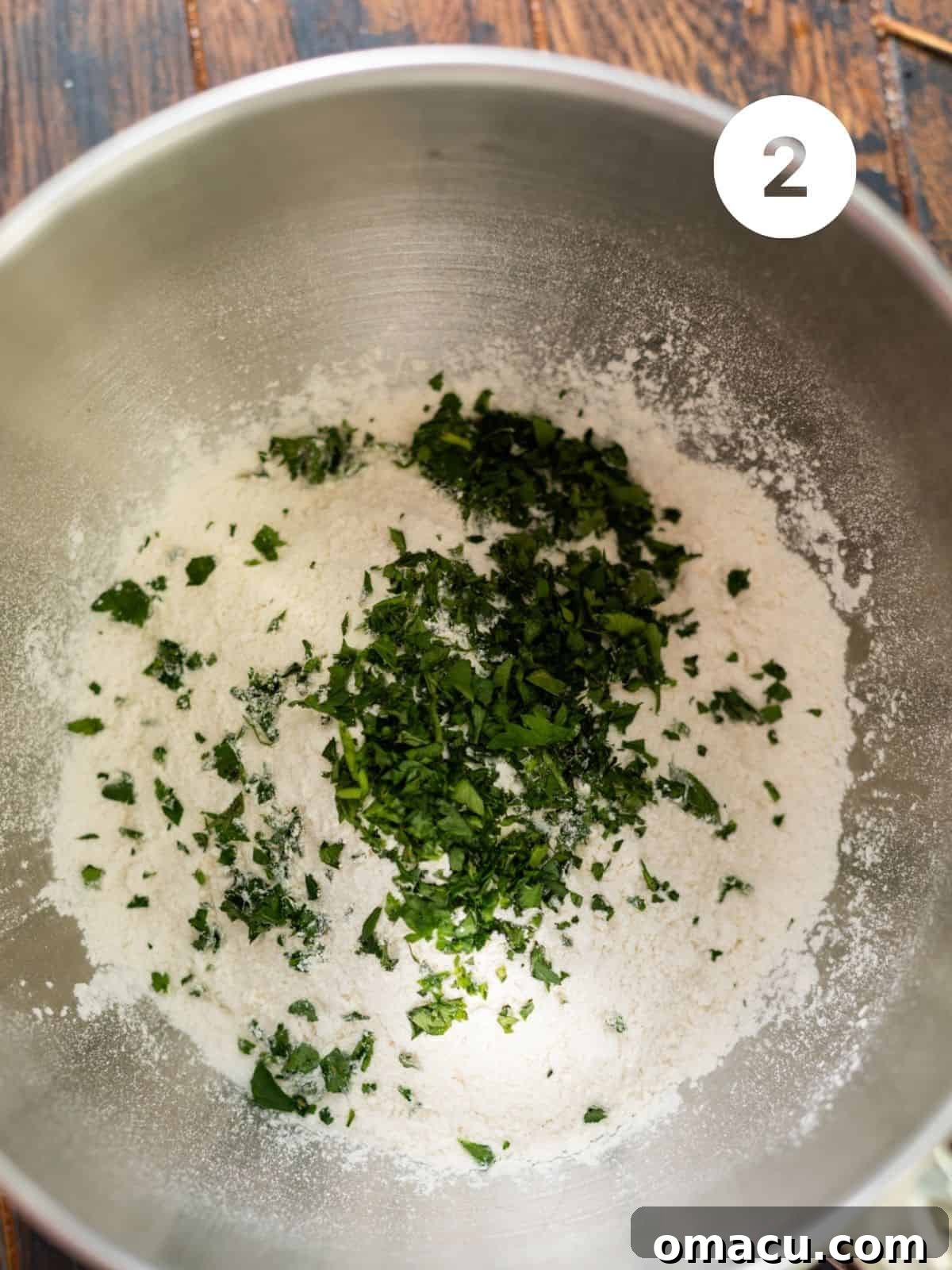 Dry ingredients including flour, garlic powder, onion powder, and parsley in the bowl of a stand mixer.