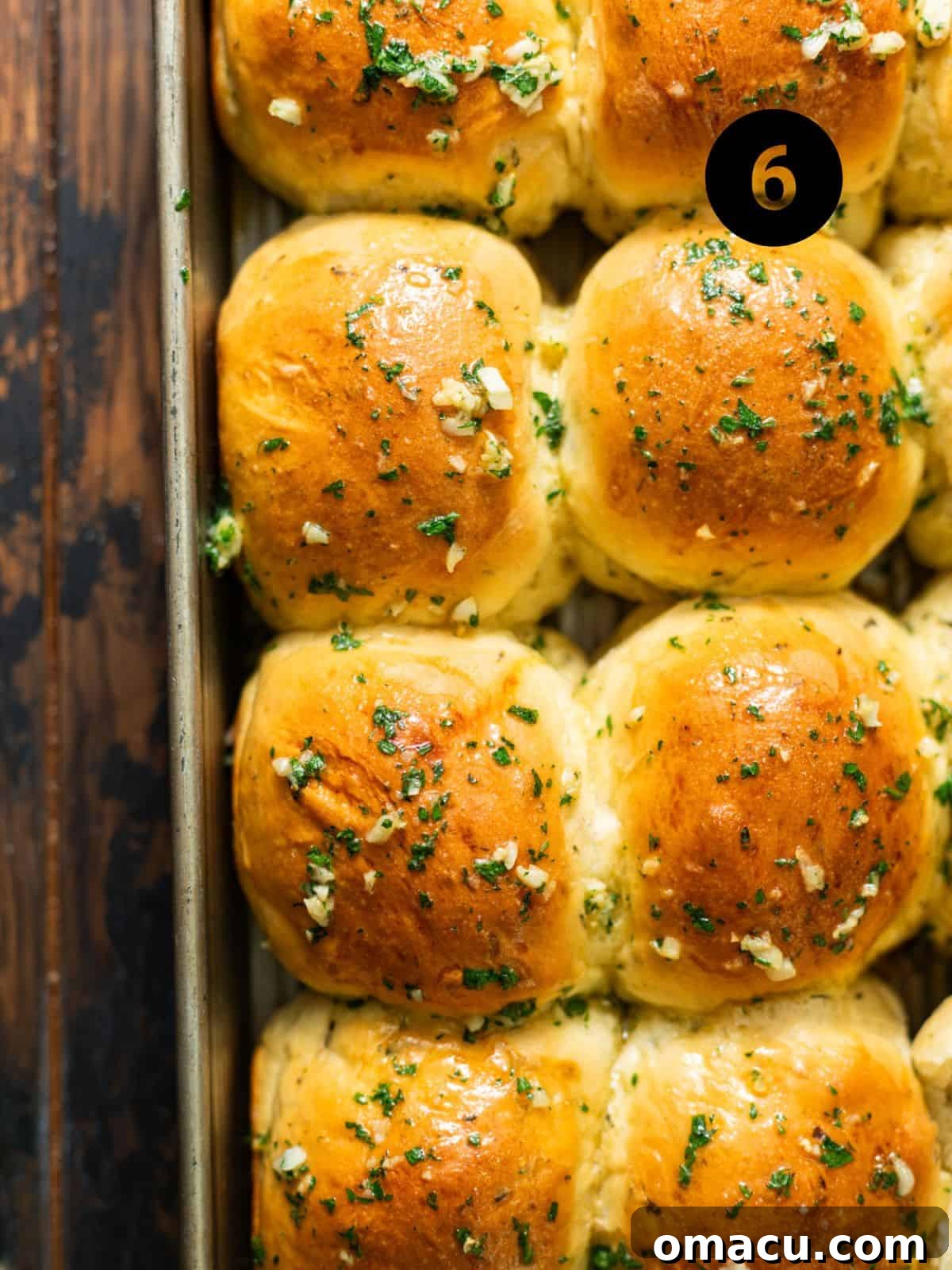 Freshly baked garlic butter rolls, golden brown and brushed with garlic butter, still in the baking pan.