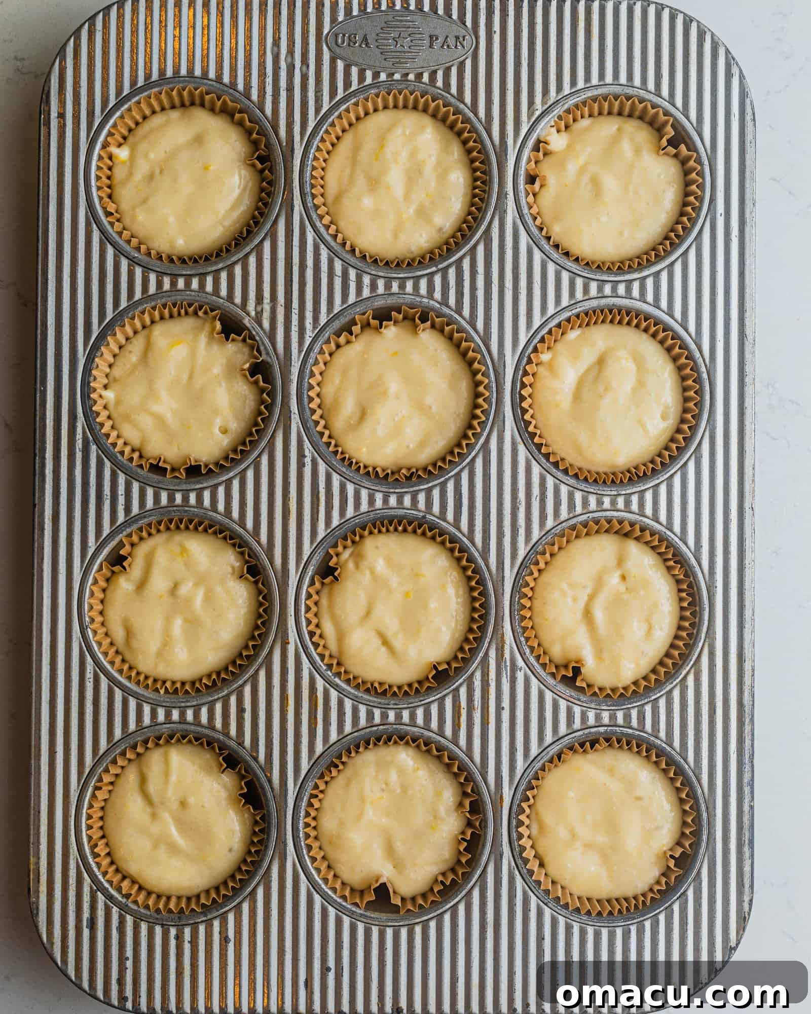 a cupcake pan lined with cupcake liners and filled with lemon raspberry cupcake batter