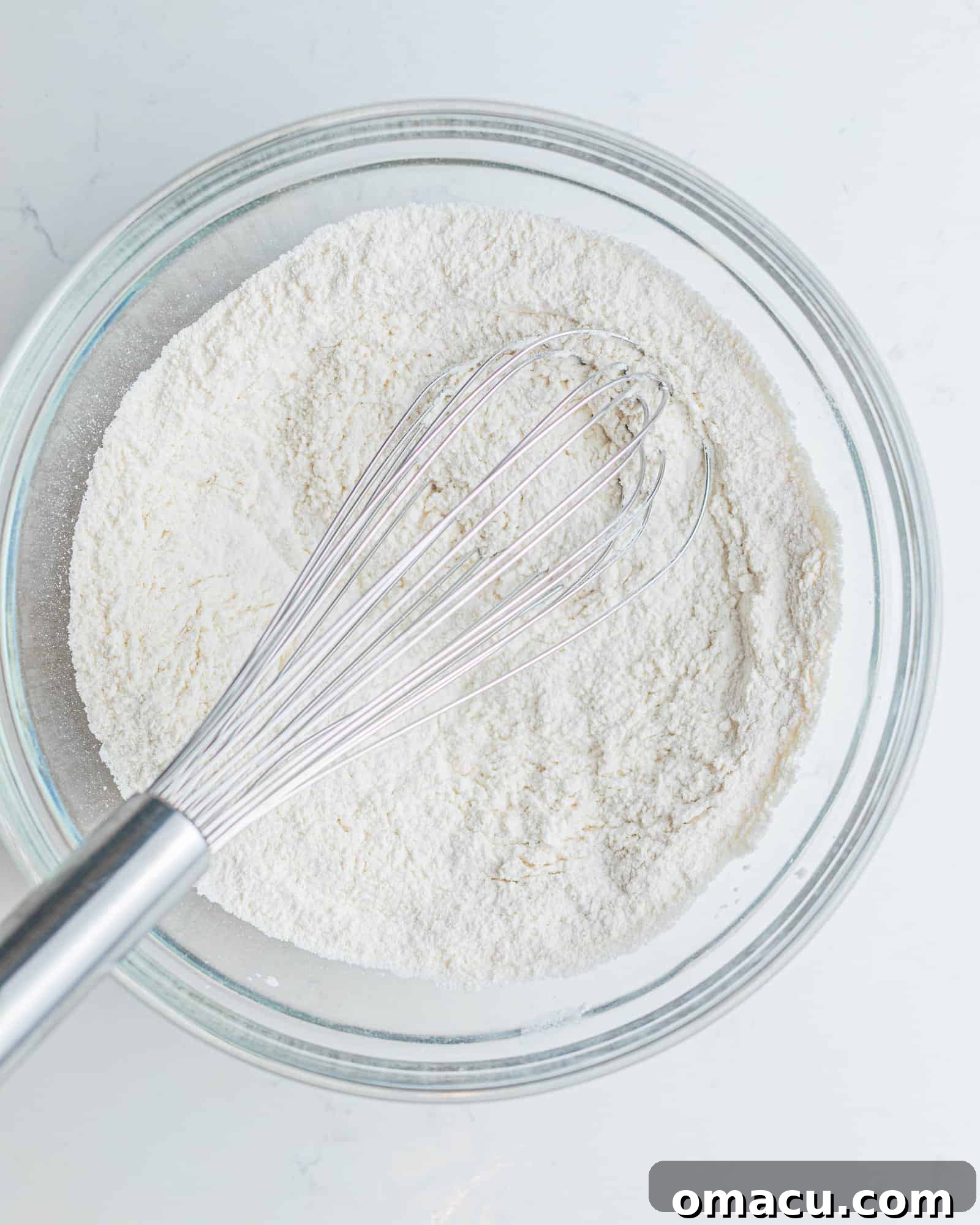 flour, baking powder, baking soda, and salt mixed together in a mixing bowl to form the dry ingredients for this cupcake recipe