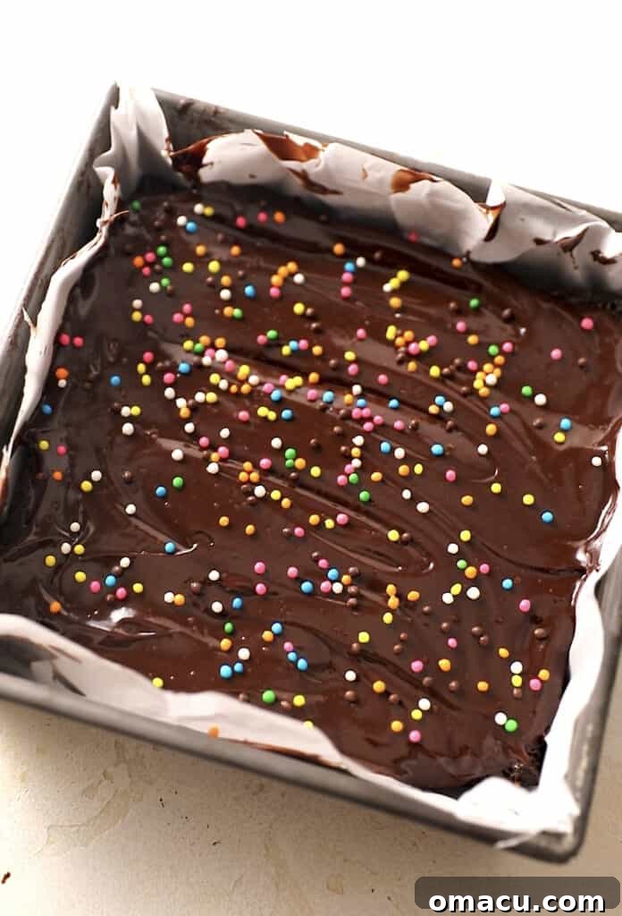 Finished cosmic brownies with vibrant rainbow crunch sprinkles, set in an 8x8 baking dish, ready to be cut.