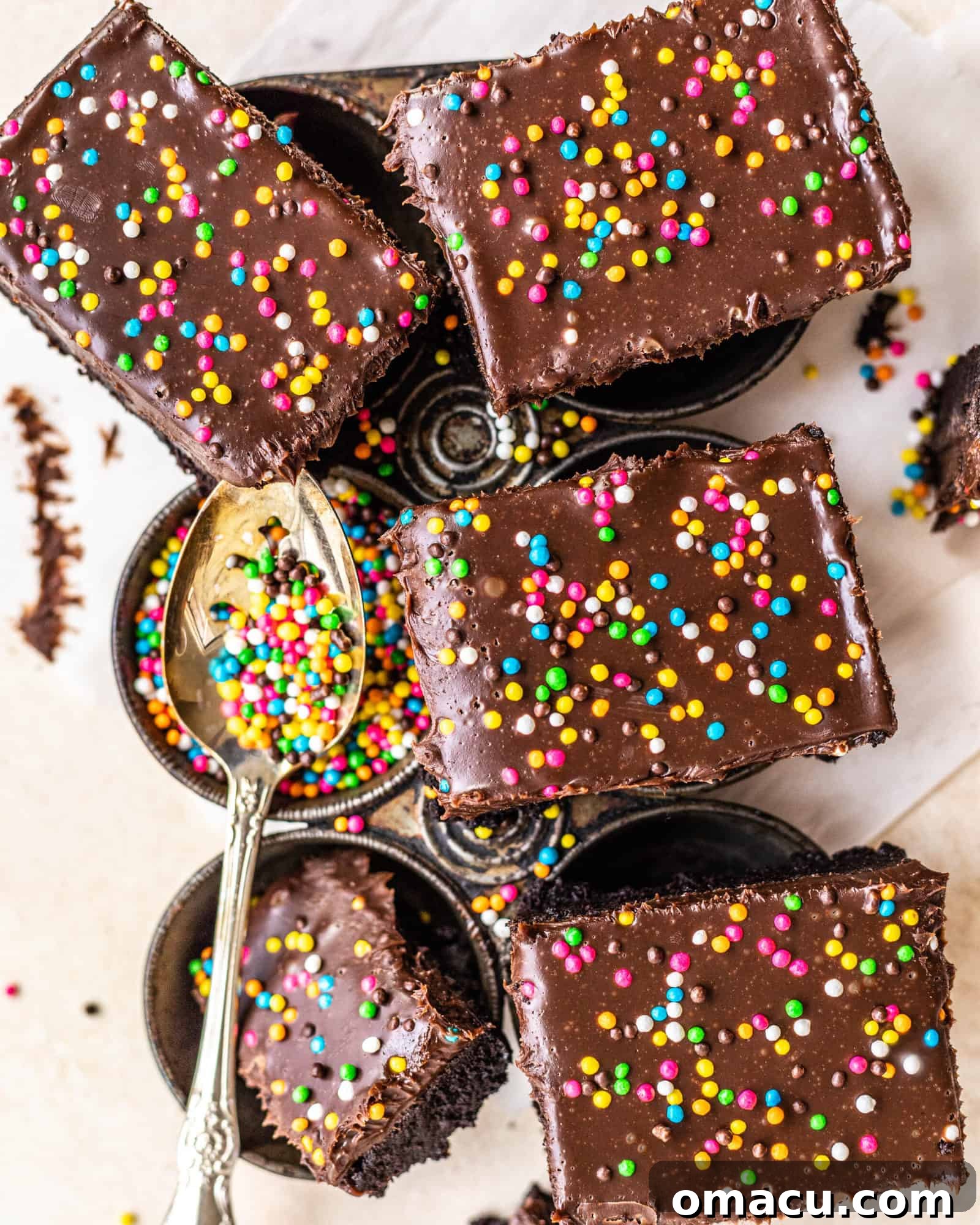 Baked brownies on top of a muffin pan, with one cup filled with colorful crunchy sprinkles, ready for garnishing.