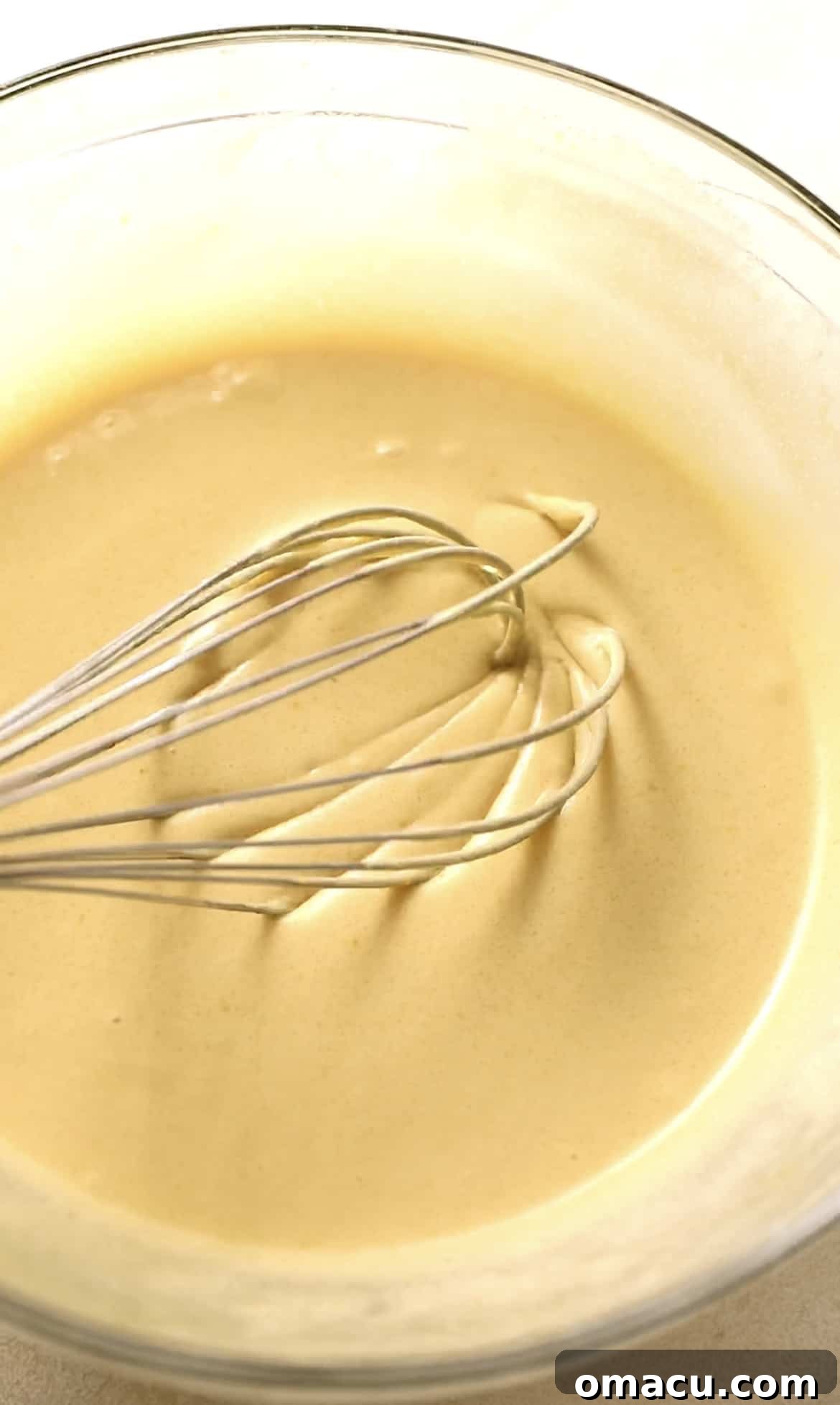 All wet ingredients for cosmic brownies, including eggs, sugars, oils, vanilla, and sour cream, perfectly whisked together in a bowl.