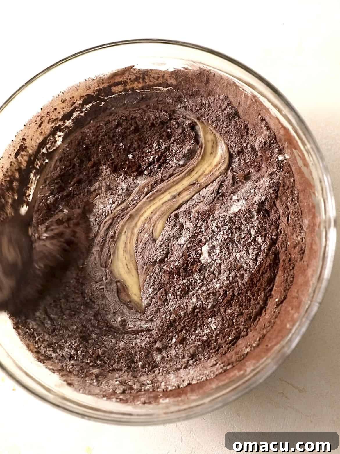 Folding cocoa powder, flour, and salt into the wet ingredients to create the rich brownie batter.