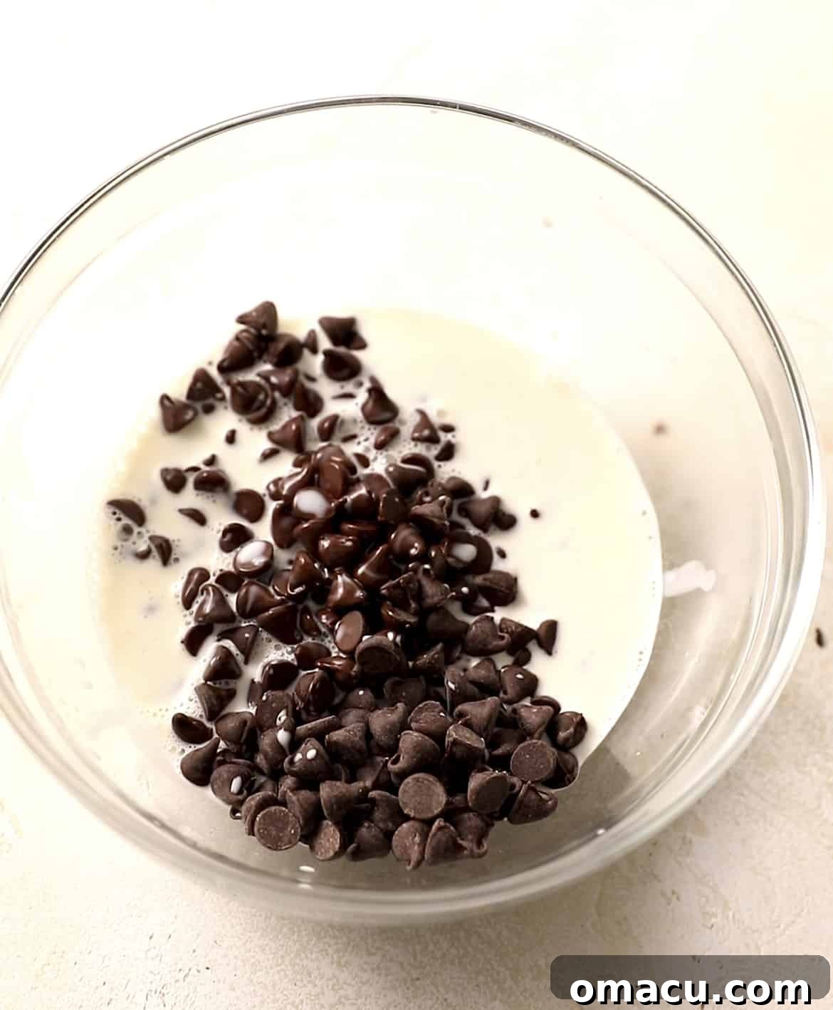 Heavy cream and chocolate chips in a bowl, ready to be heated and whisked into a rich chocolate ganache.