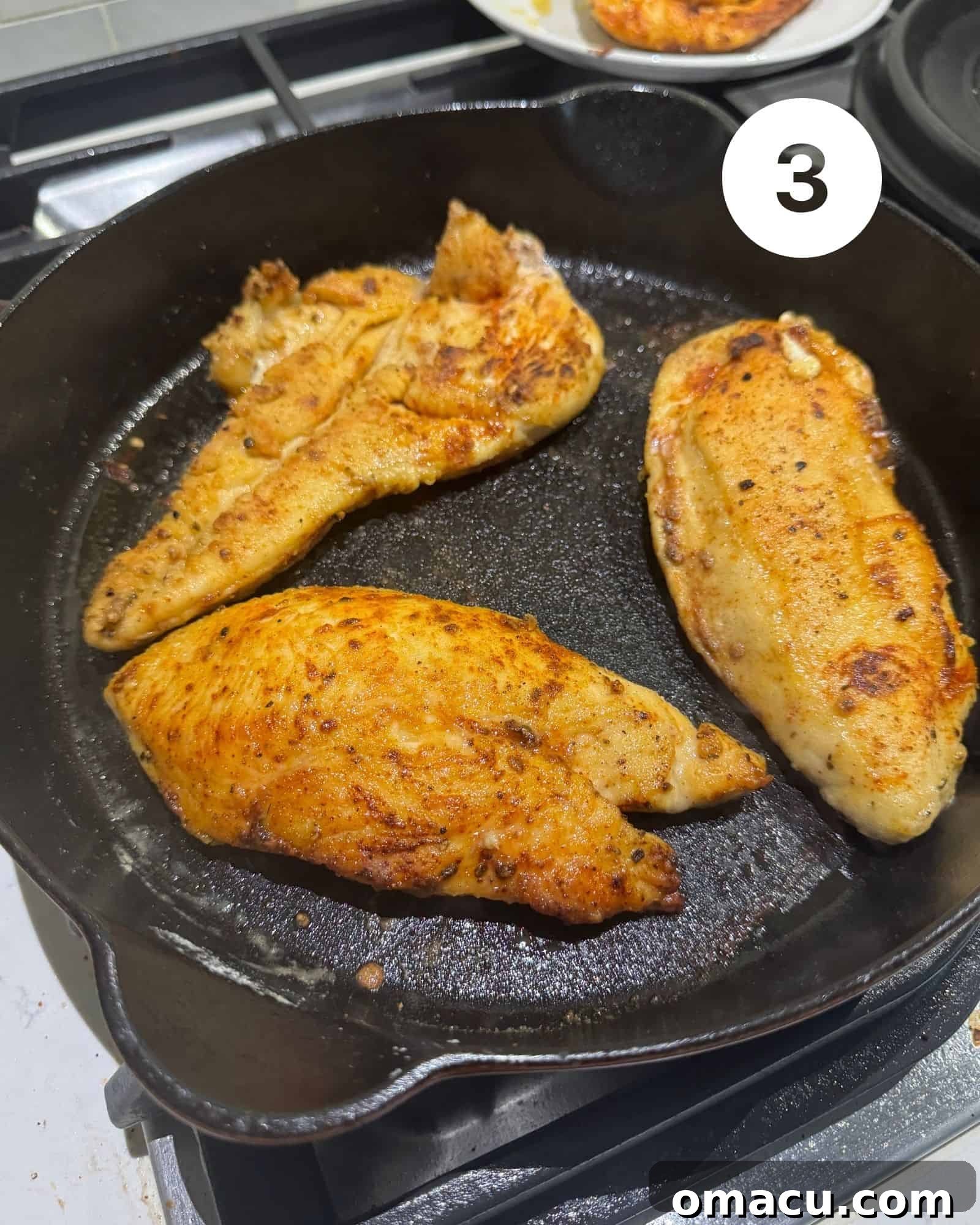 Golden-brown, perfectly seared chicken pieces sizzling in a robust cast iron skillet, radiating a delicious aroma.