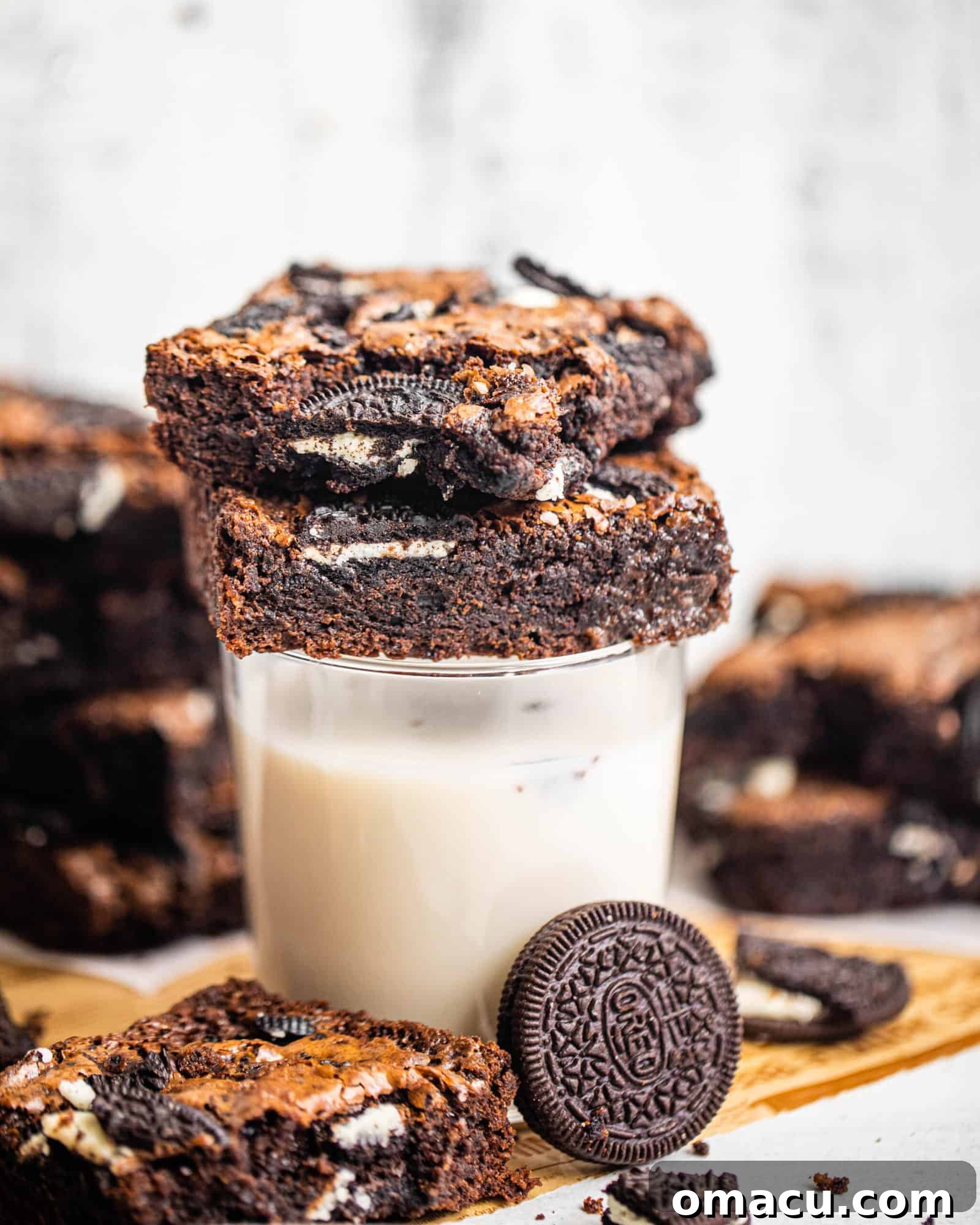 Stack of fudgy Oreo brownies next to a glass of milk, a classic pairing for this decadent dessert.