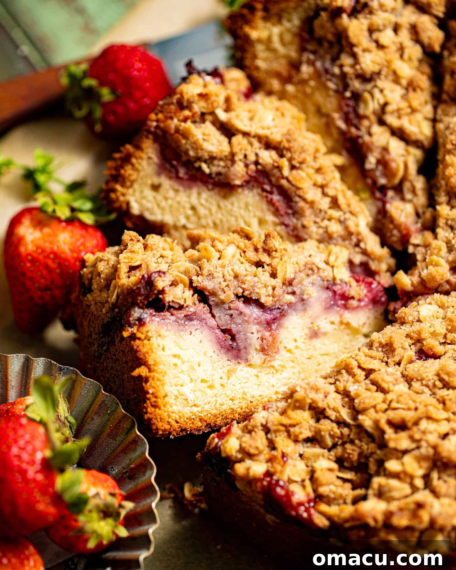 A perfectly sliced strawberry crumb cake, showcasing its layers of soft cake, fresh strawberries, and golden crumb topping, resting on a piece of parchment paper, ready to be served.