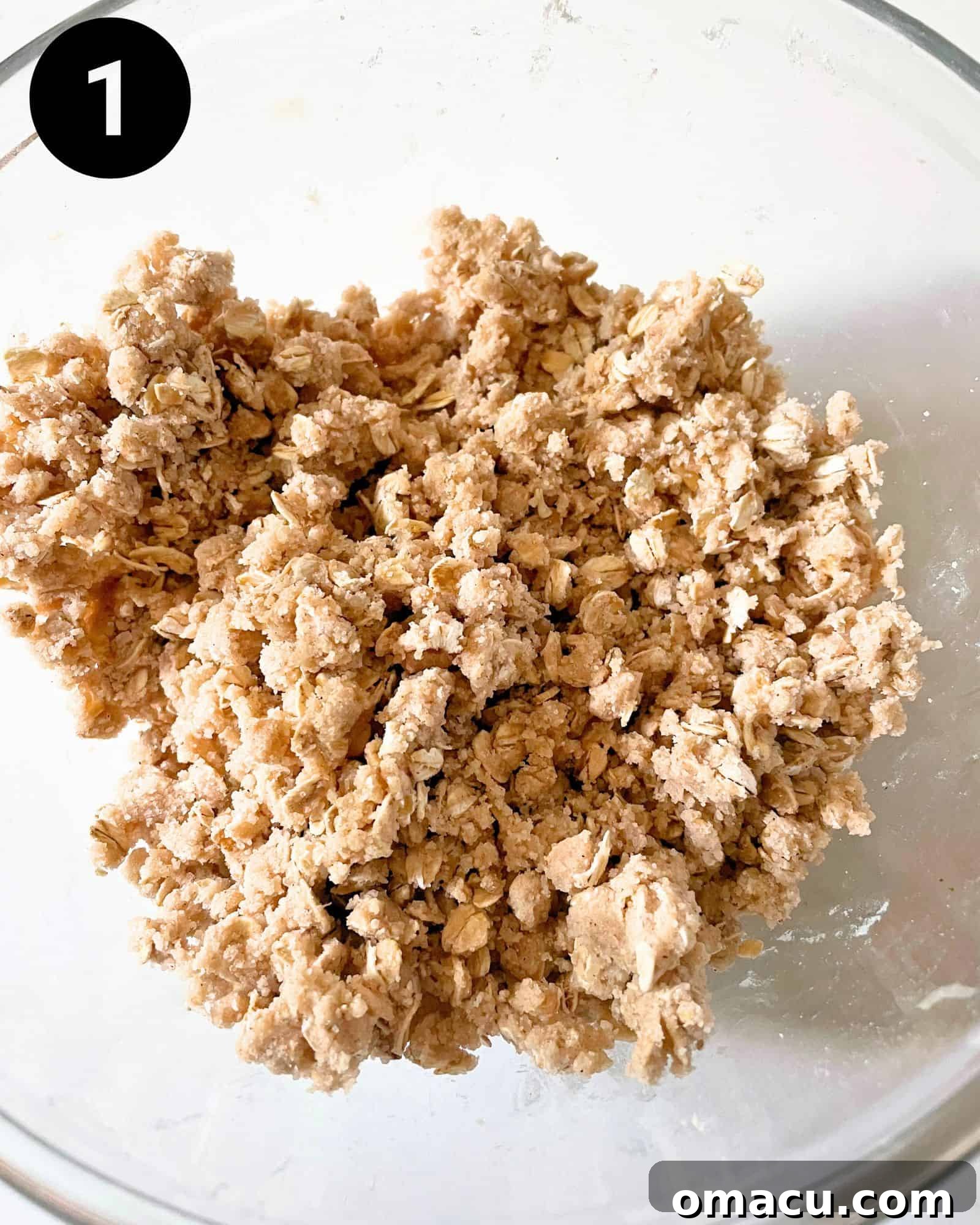 A bowl filled with the prepared strawberry crumb cake topping, showing its rough, crumbly texture, ready to be sprinkled over the cake batter.