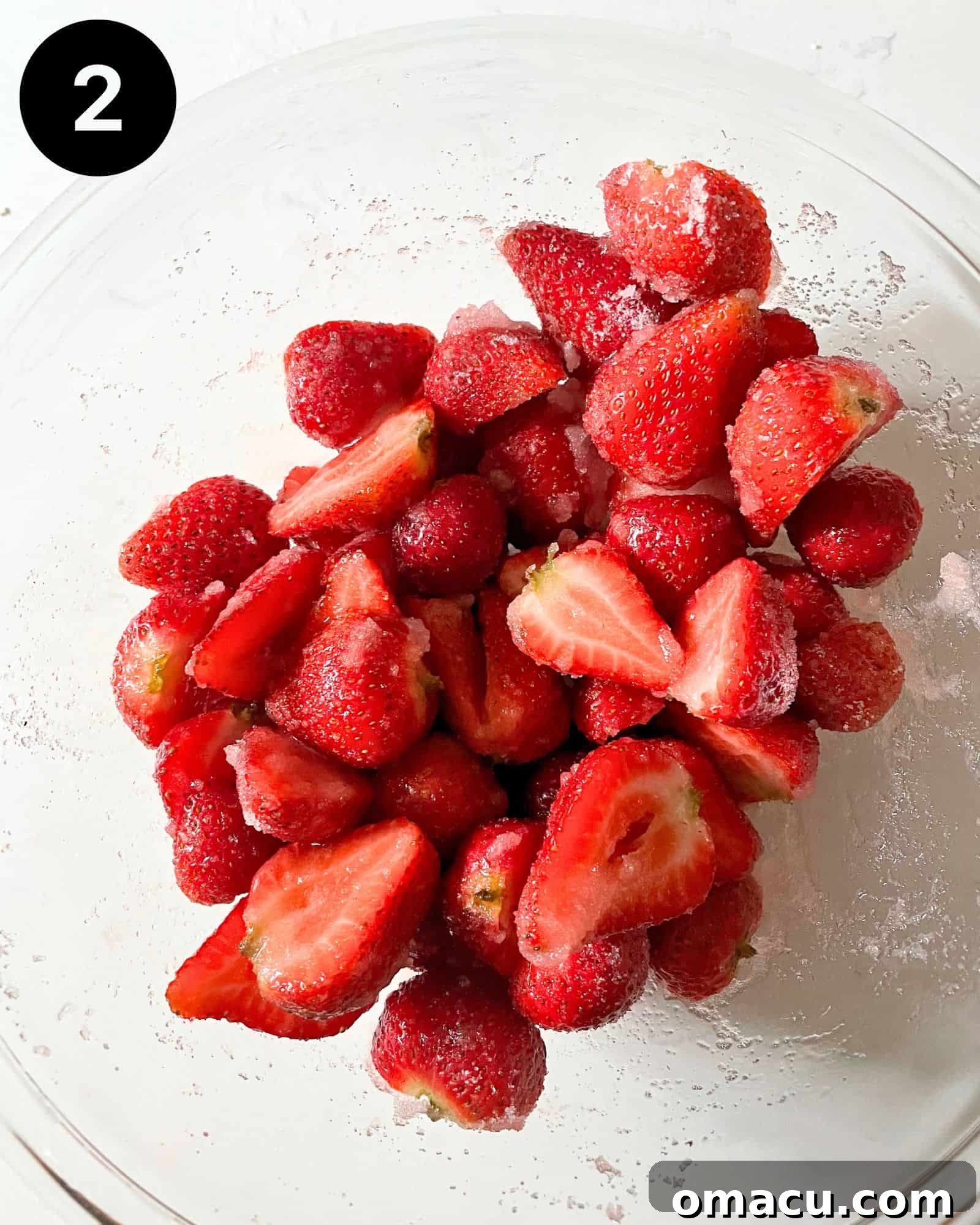 Freshly cut strawberries in a mixing bowl, lightly coated with sugar and cornstarch, prepared as the luscious filling for the crumb cake.