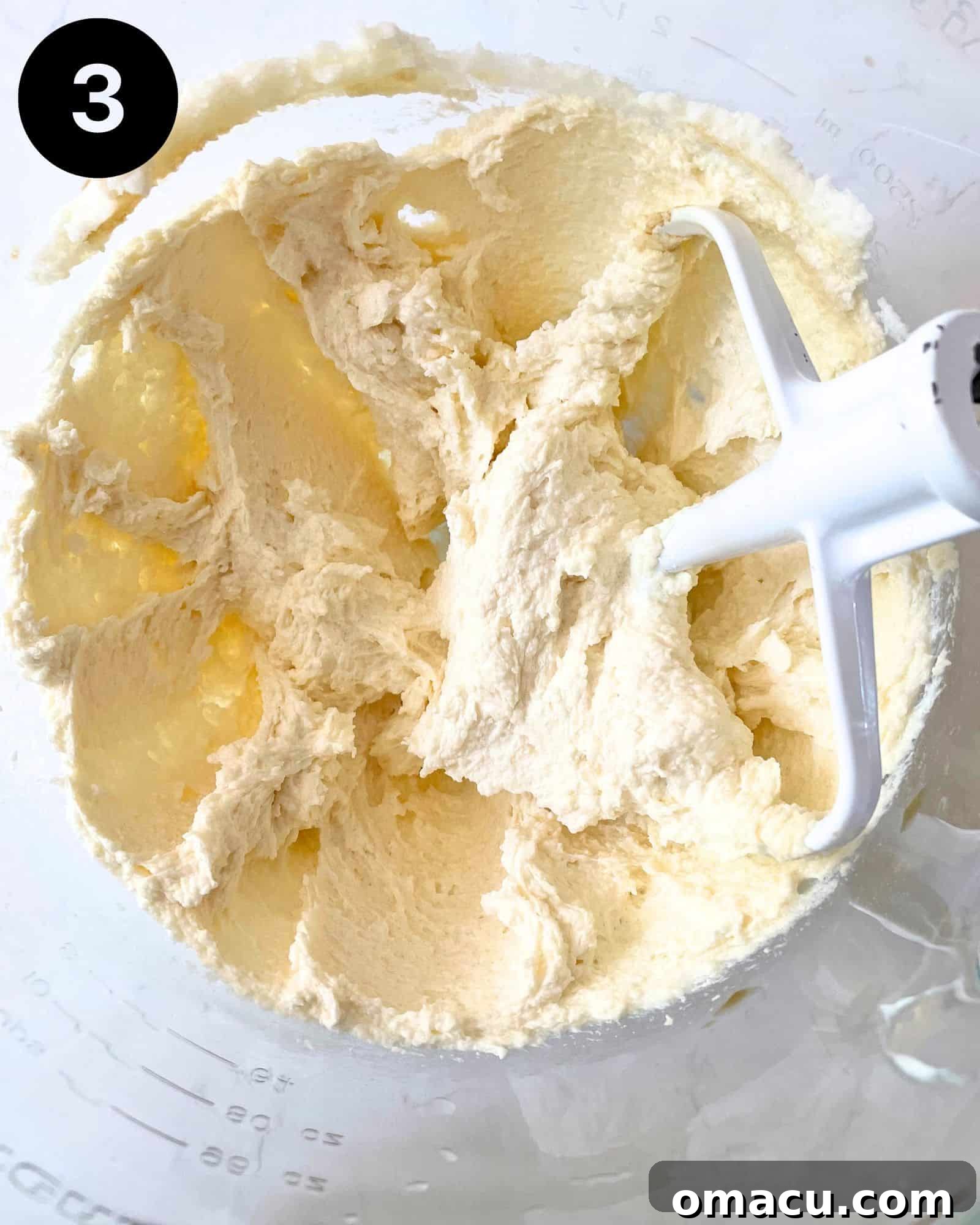 Room temperature butter and granulated sugar perfectly creamed together in the bowl of a stand mixer, demonstrating the light and fluffy texture achieved with the paddle attachment.