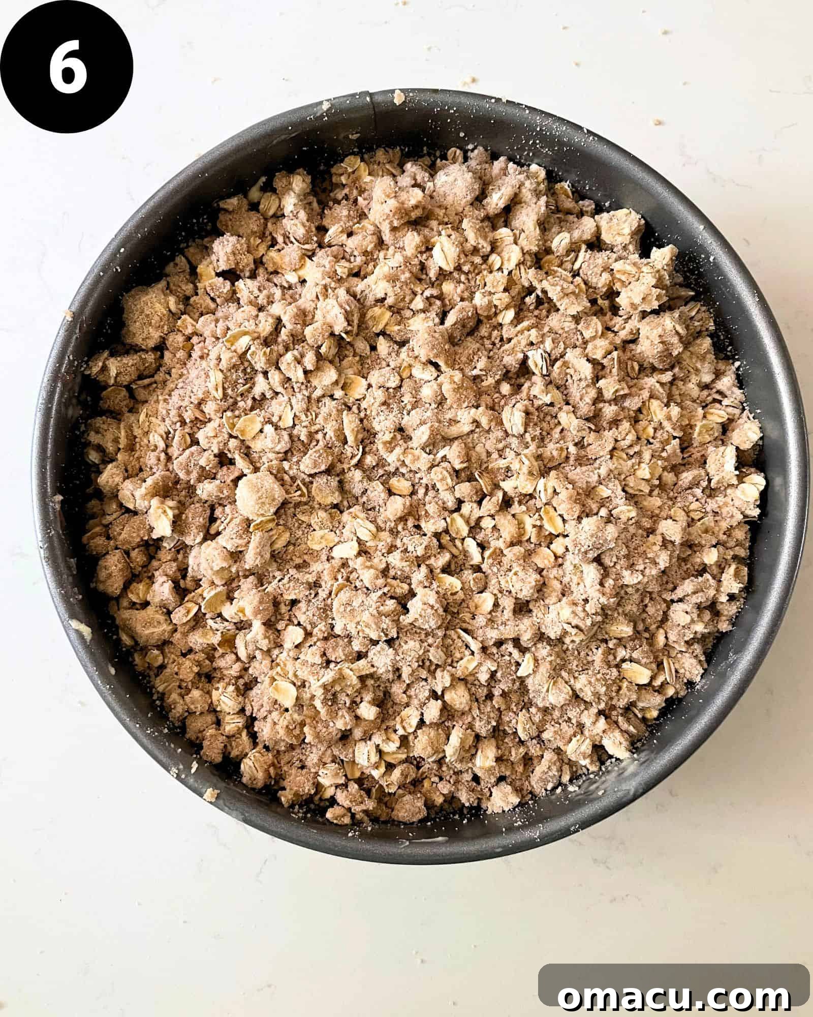 The complete strawberry crumb cake assembled in a springform pan, featuring a base of cake batter, a layer of strawberries, and a generous, even sprinkle of golden crumb topping, ready for baking.