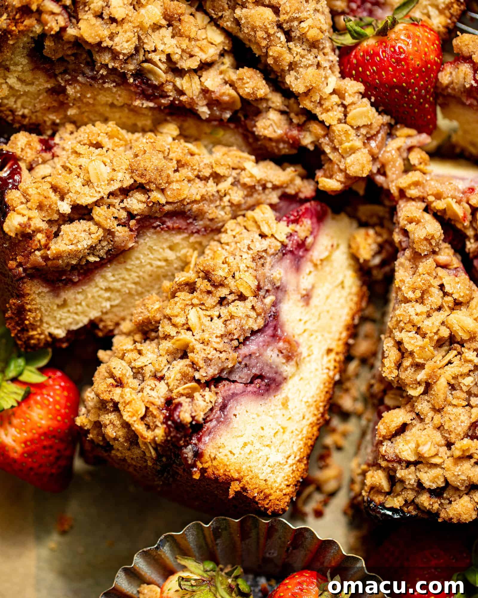 A large, beautifully baked strawberry crumb cake slice resting on a stylish serving board, highlighting its appealing golden crust and inviting texture.