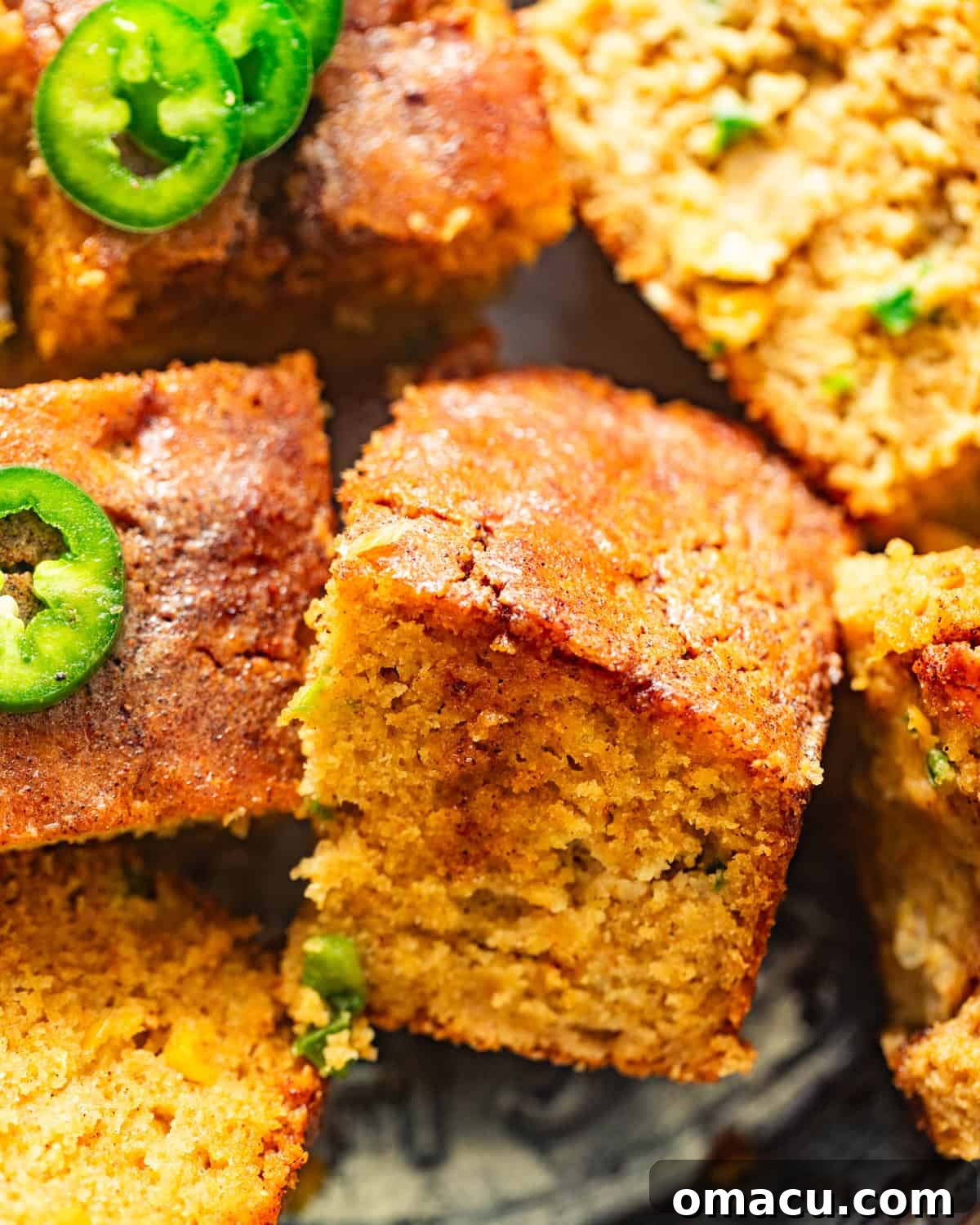 sliced honey jalapeno cornbread on a pie plate with honey butter and jalapenos on top. 