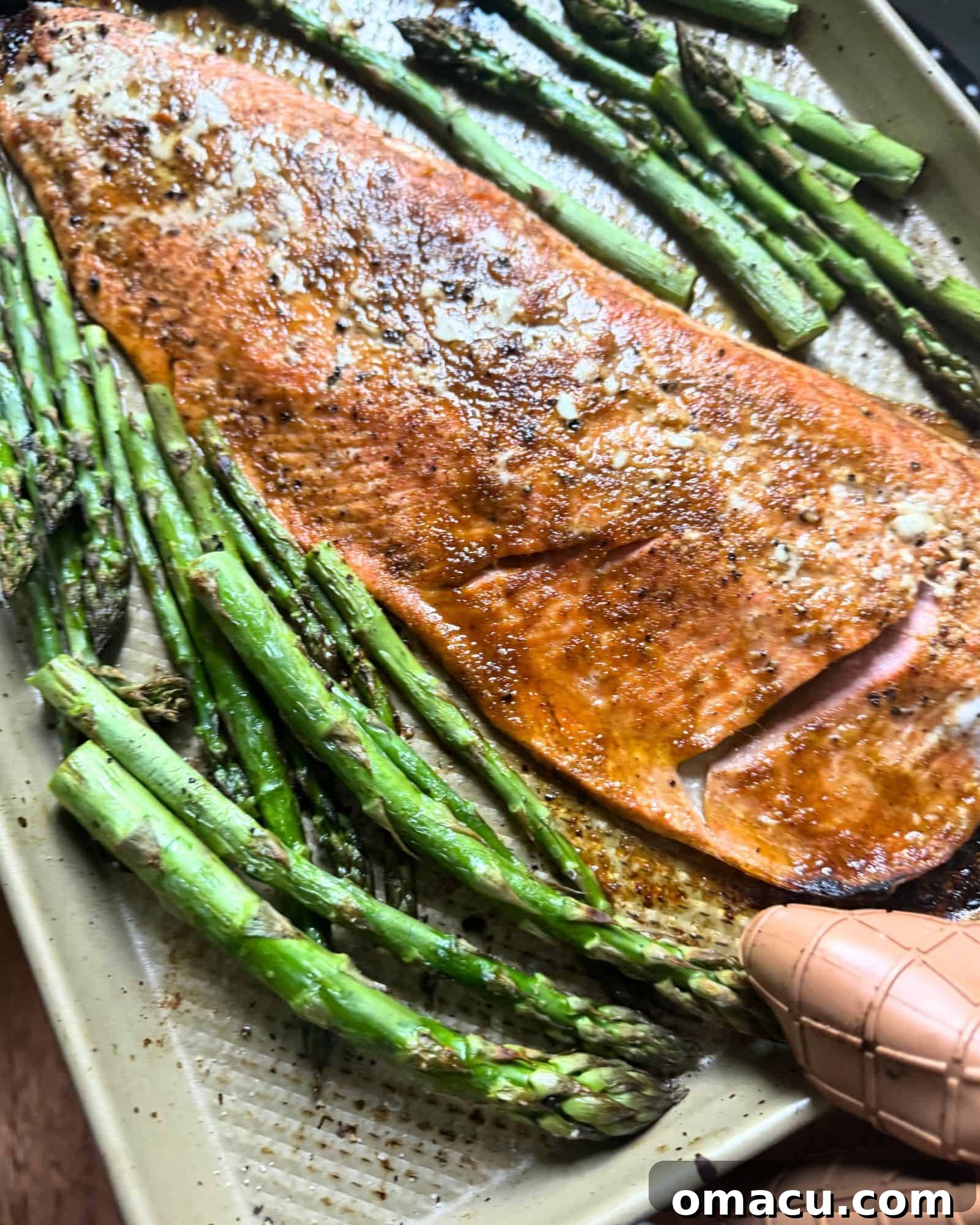 Baked salmon fillets and roasted asparagus on a sheet pan, cooked to perfection.